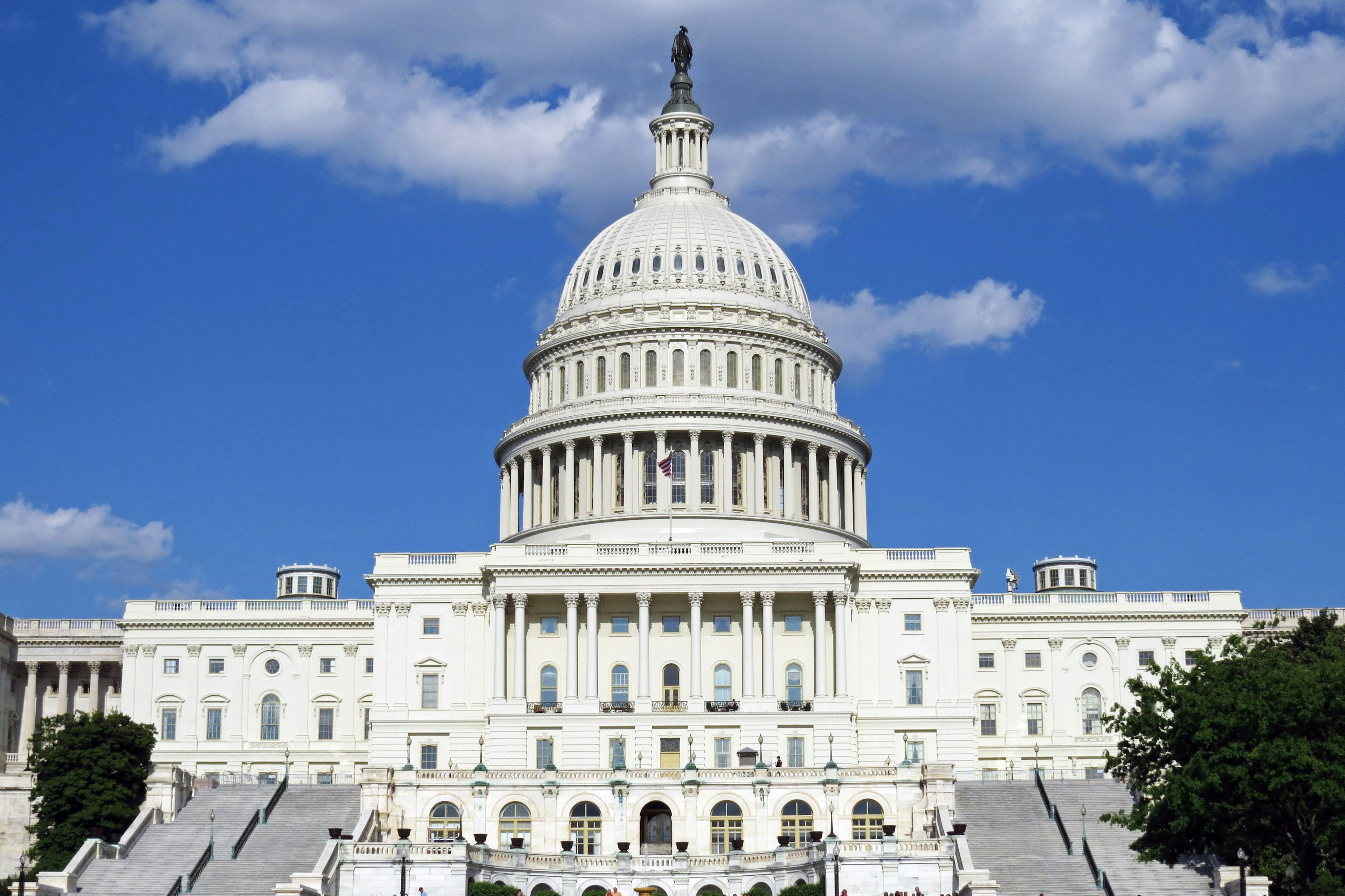 Front view of the United States Capitol building Bright white dome against a blue sky