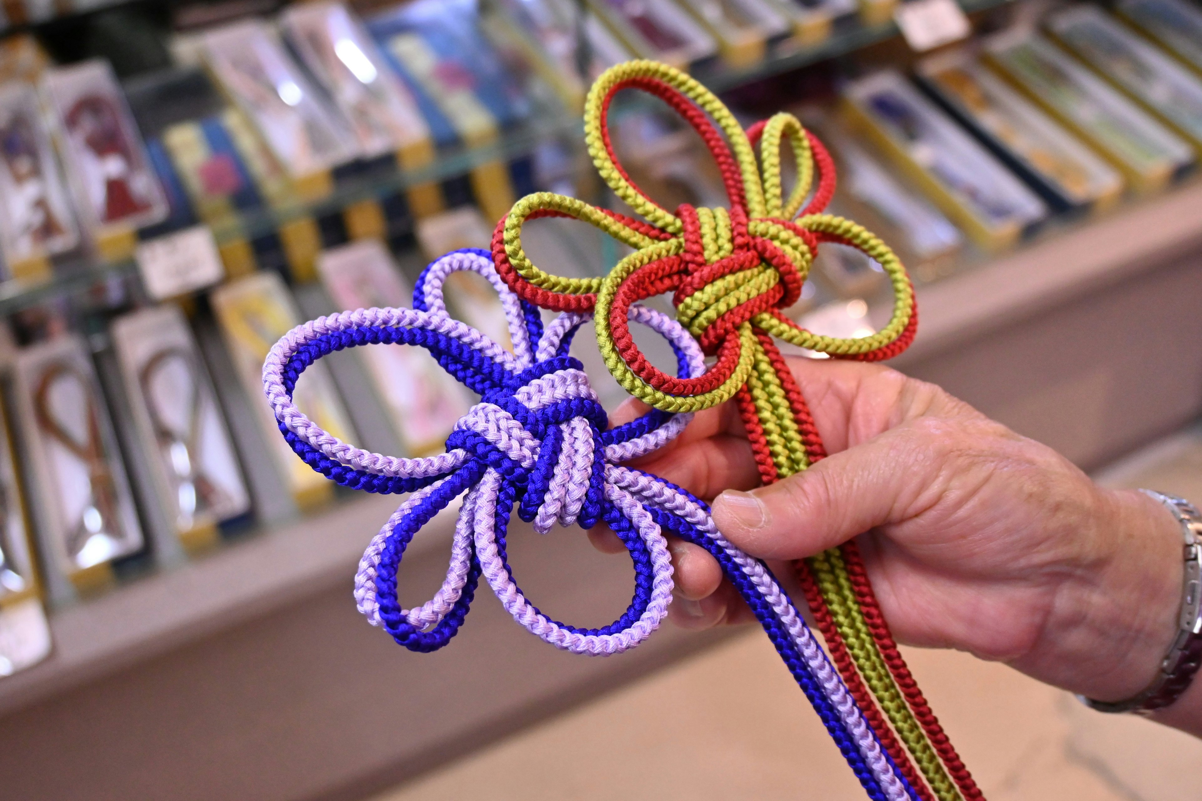 Hand holding purple and red flower-shaped knots