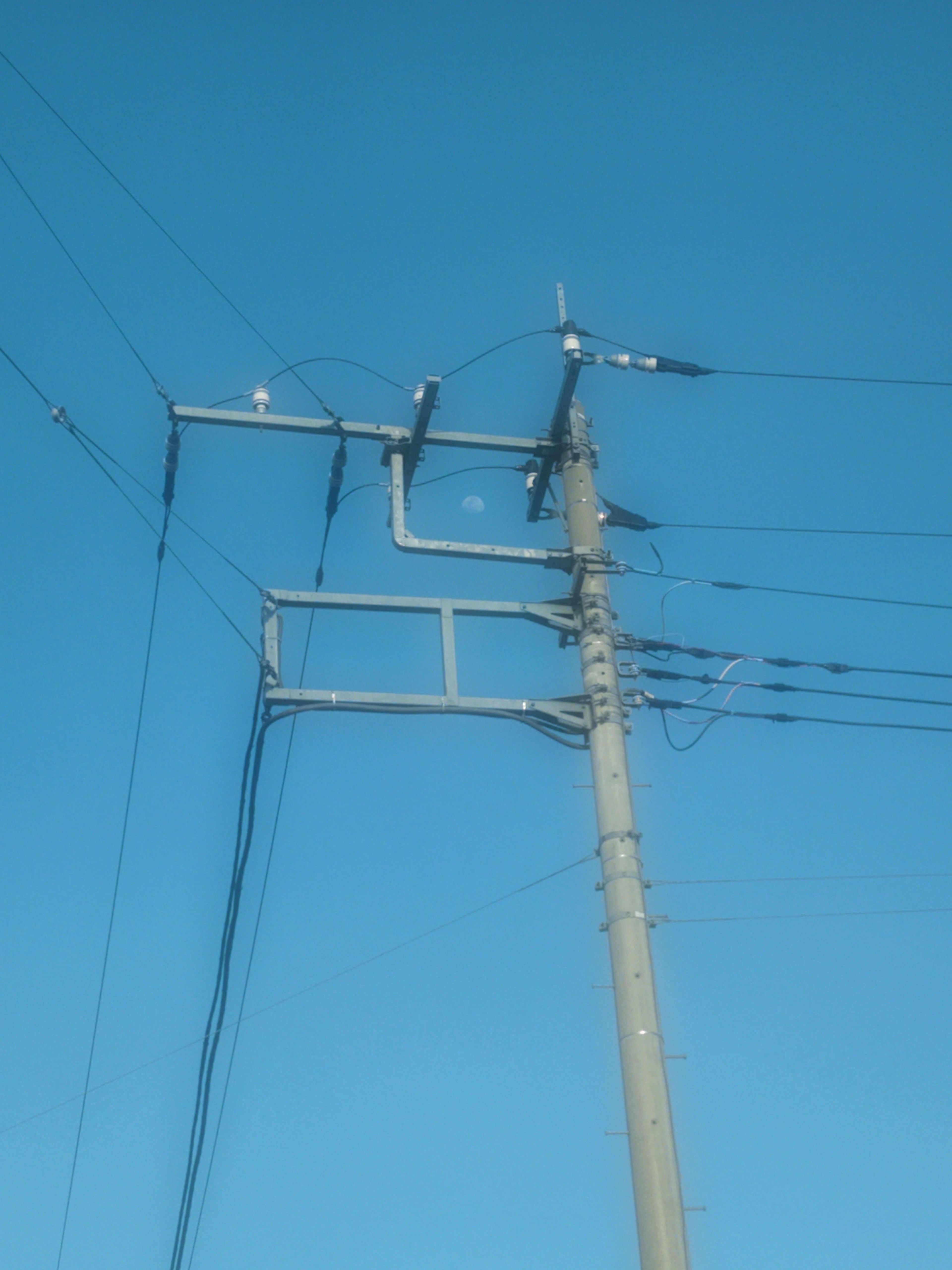 Palo della luce con cavi elettrici contro un cielo blu chiaro