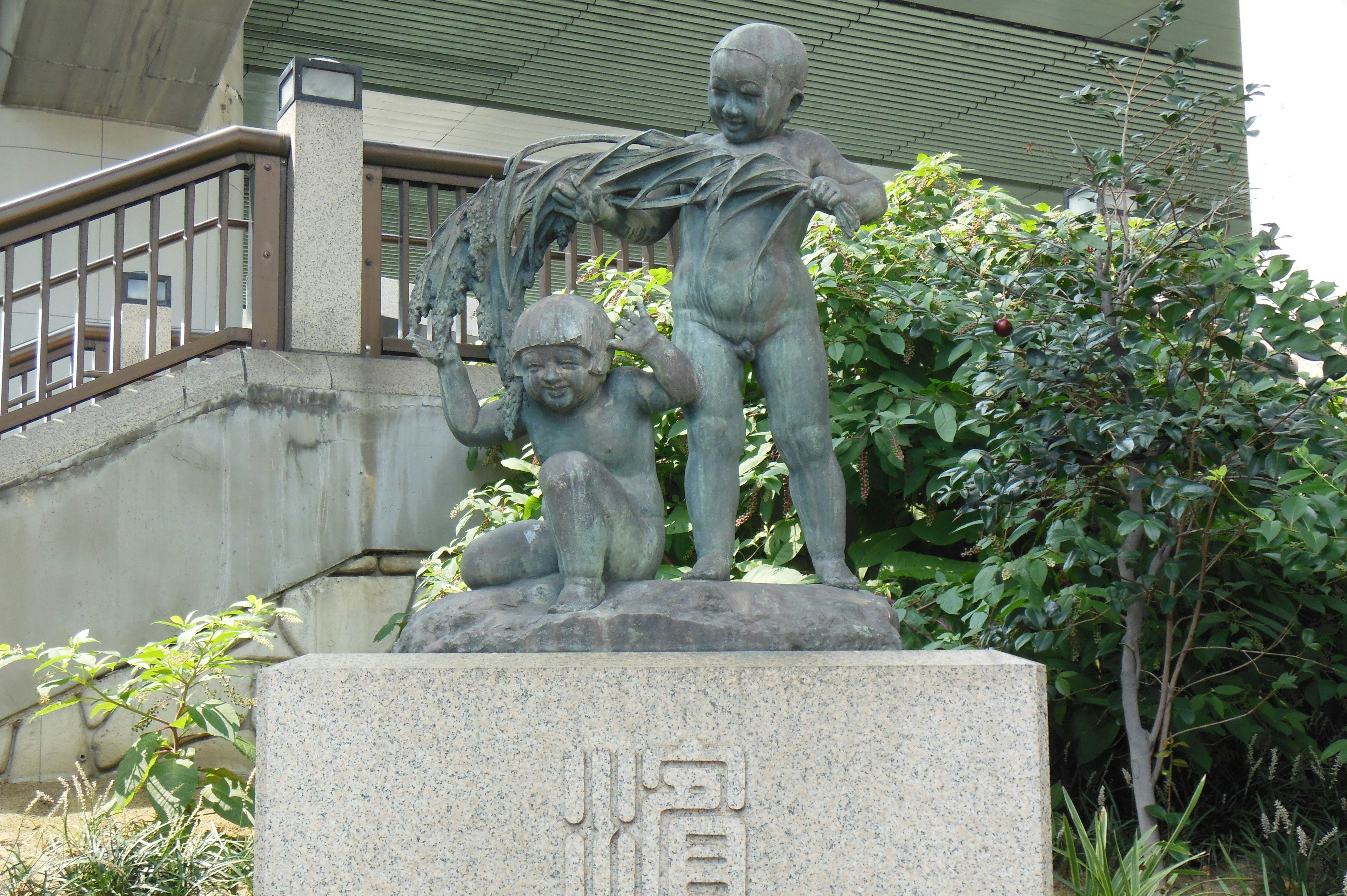 Sculpture en bronze d'enfants jouant avec de l'herbe