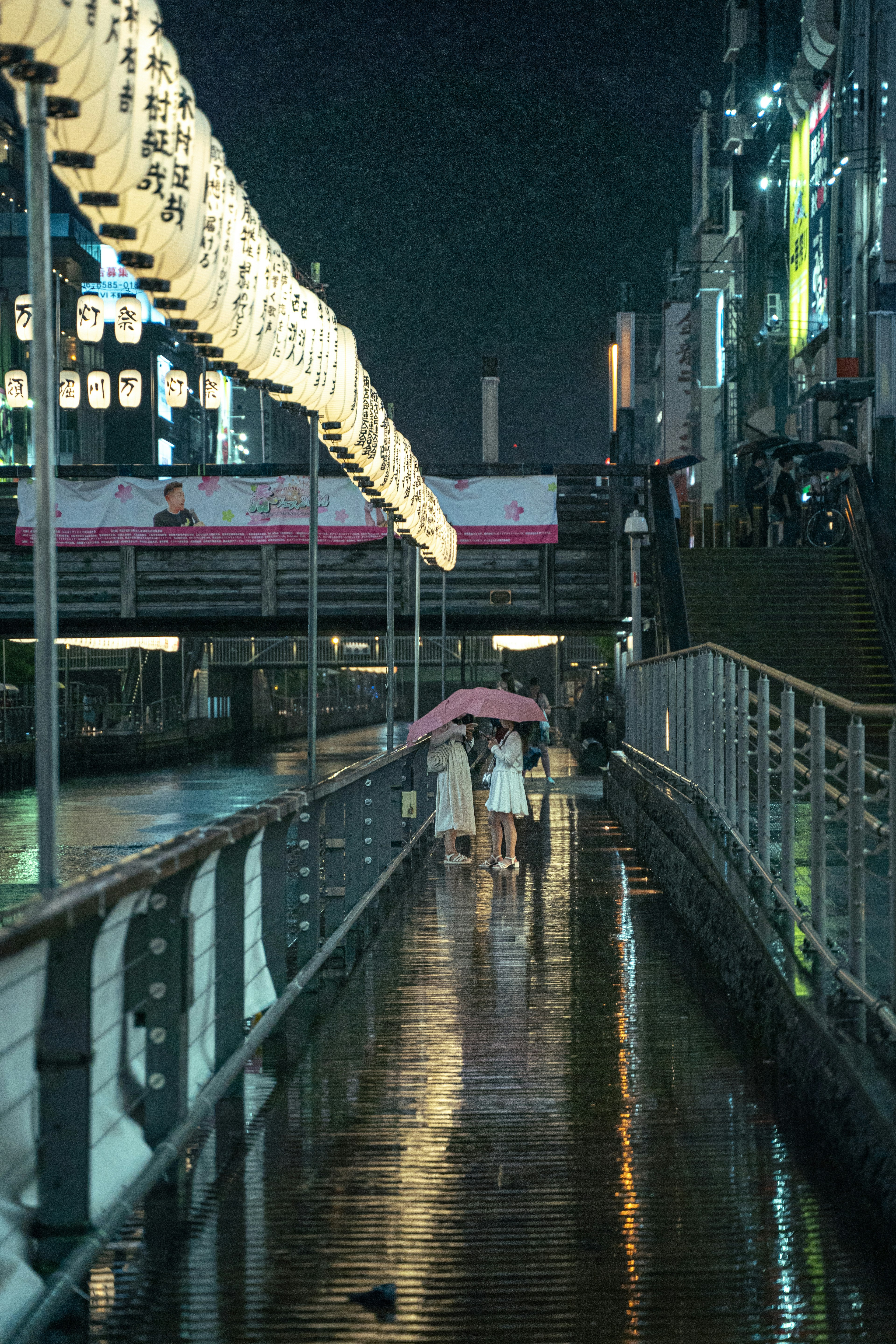 夜の街を歩く傘を持った人々と反射する水面