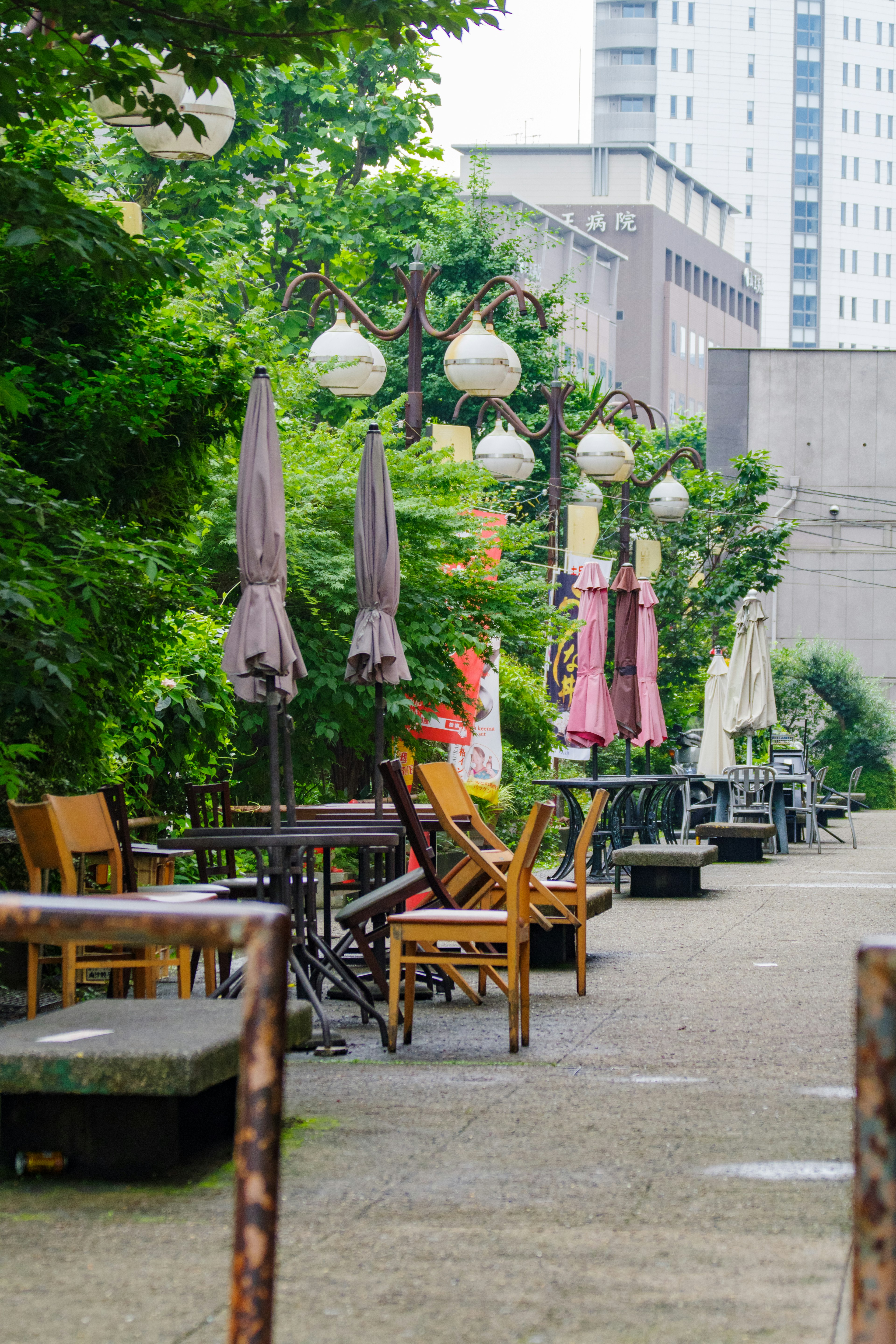 Une terrasse de café entourée de verdure avec des chaises et des tables sous des parasols