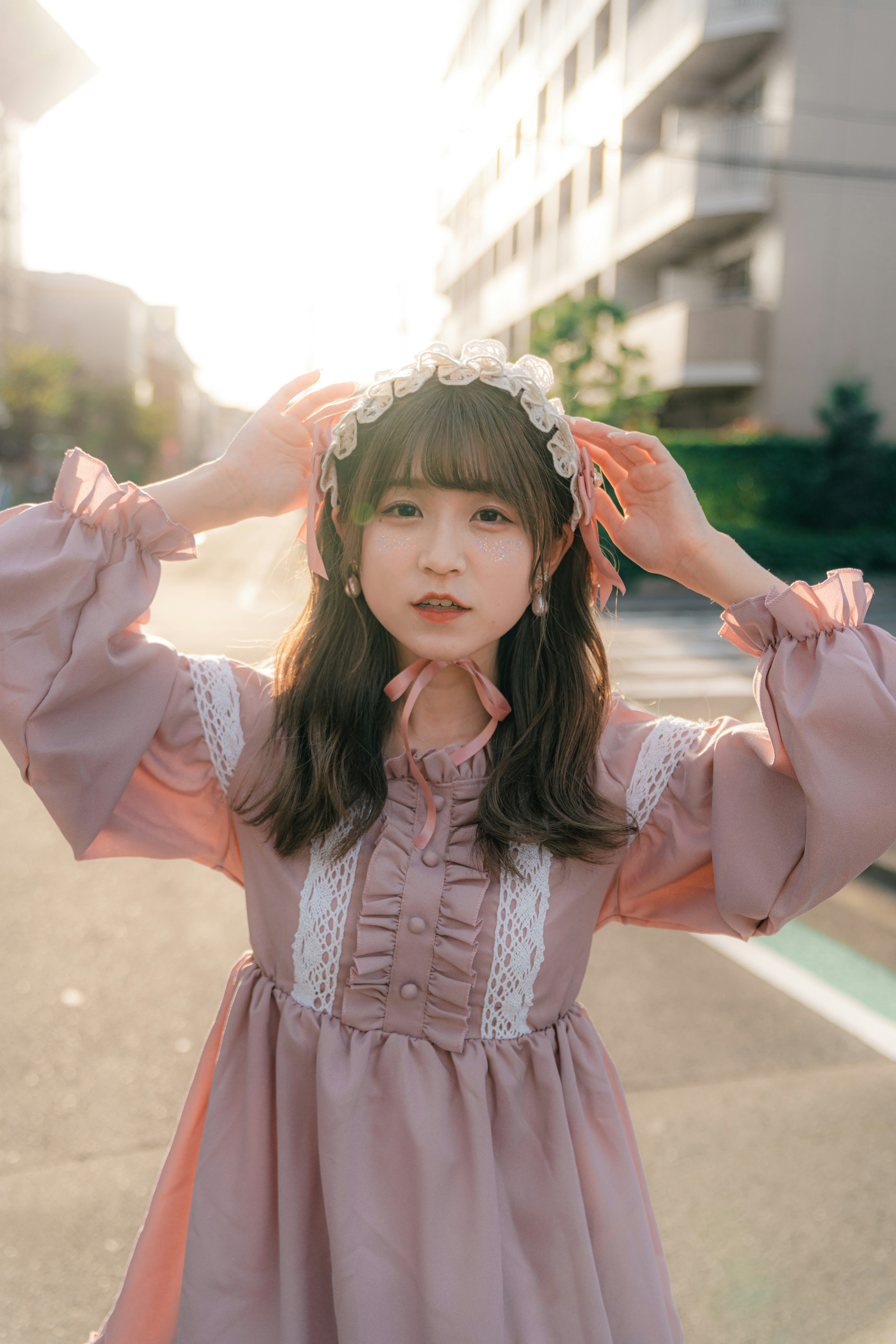 A woman posing in a pink dress on a city street