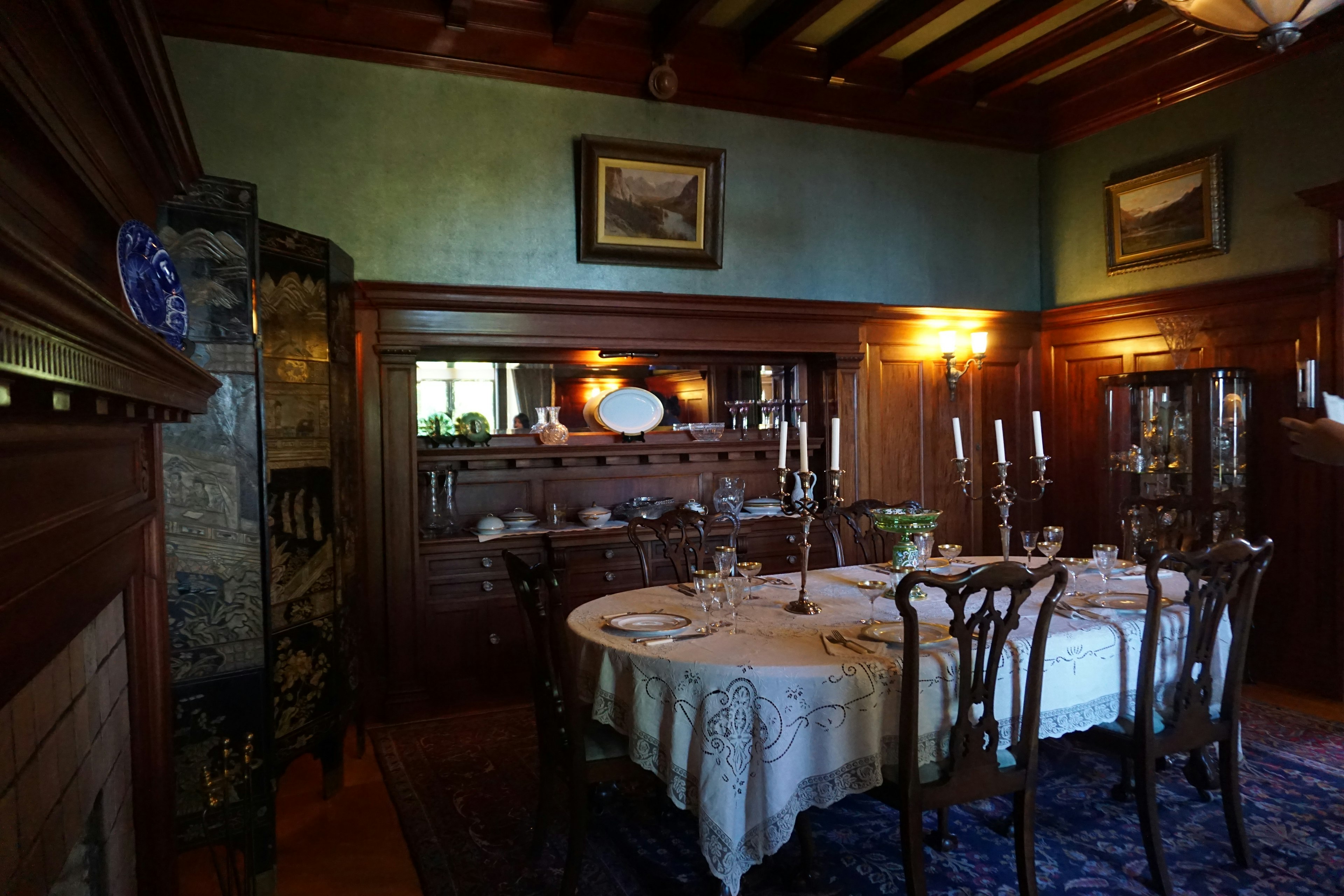 Elegant dining room featuring wooden furniture Table set with dishware and candles Paintings adorn the walls