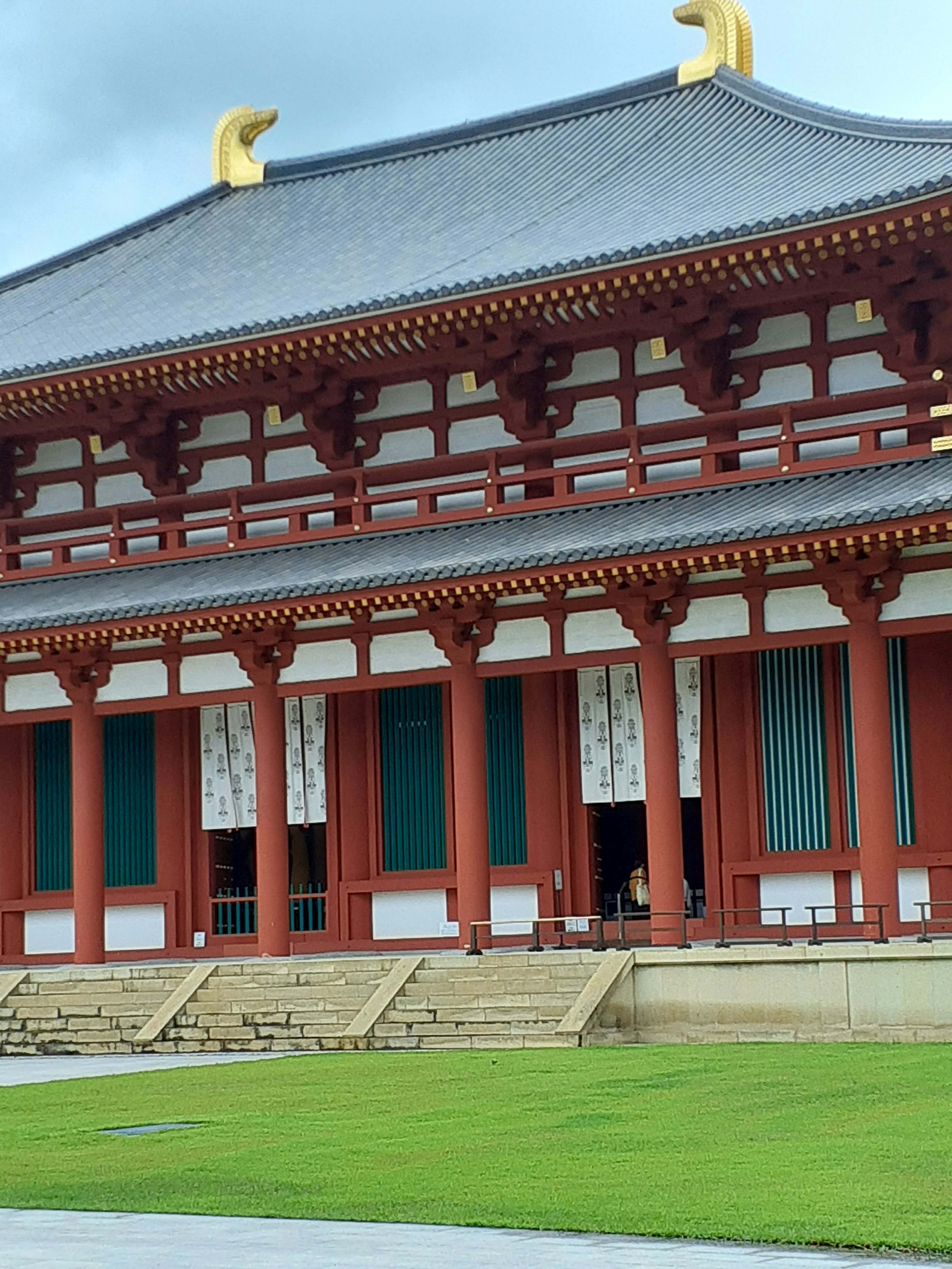 Traditional Japanese temple architecture featuring red columns and green grass