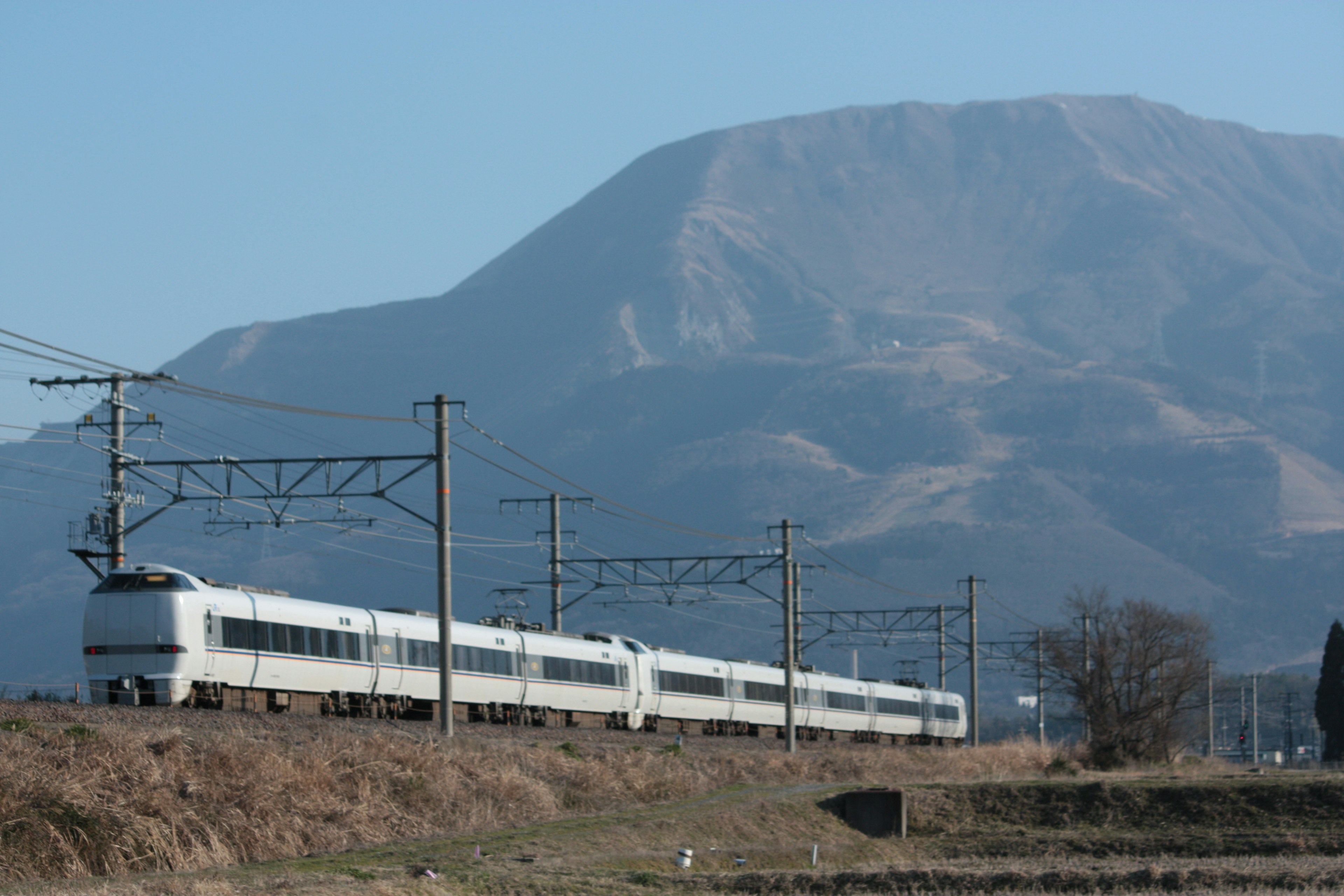 Un tren expreso blanco corriendo con un fondo montañoso