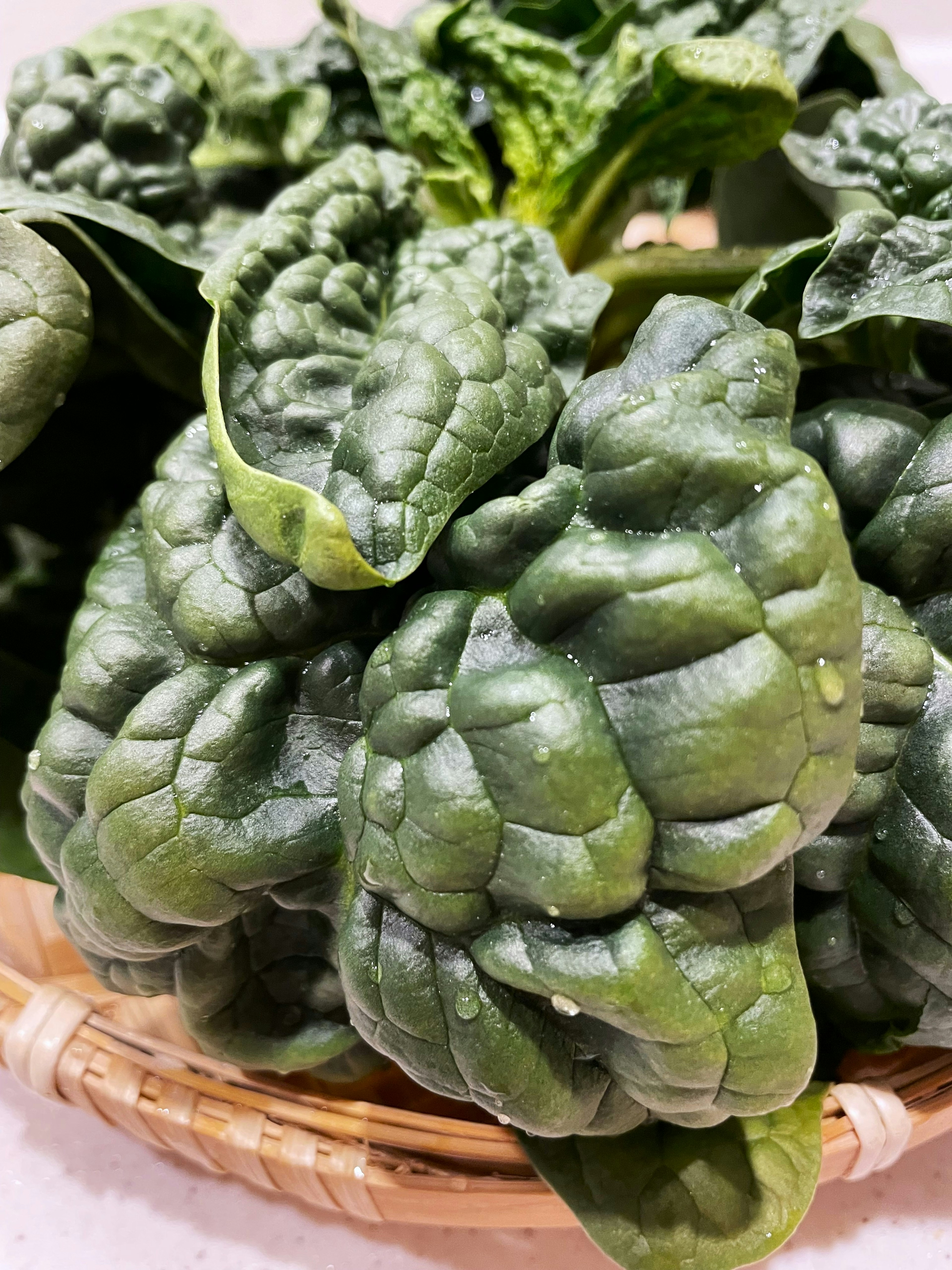 Foglie di spinaci freschi disposte in un cesto intrecciato