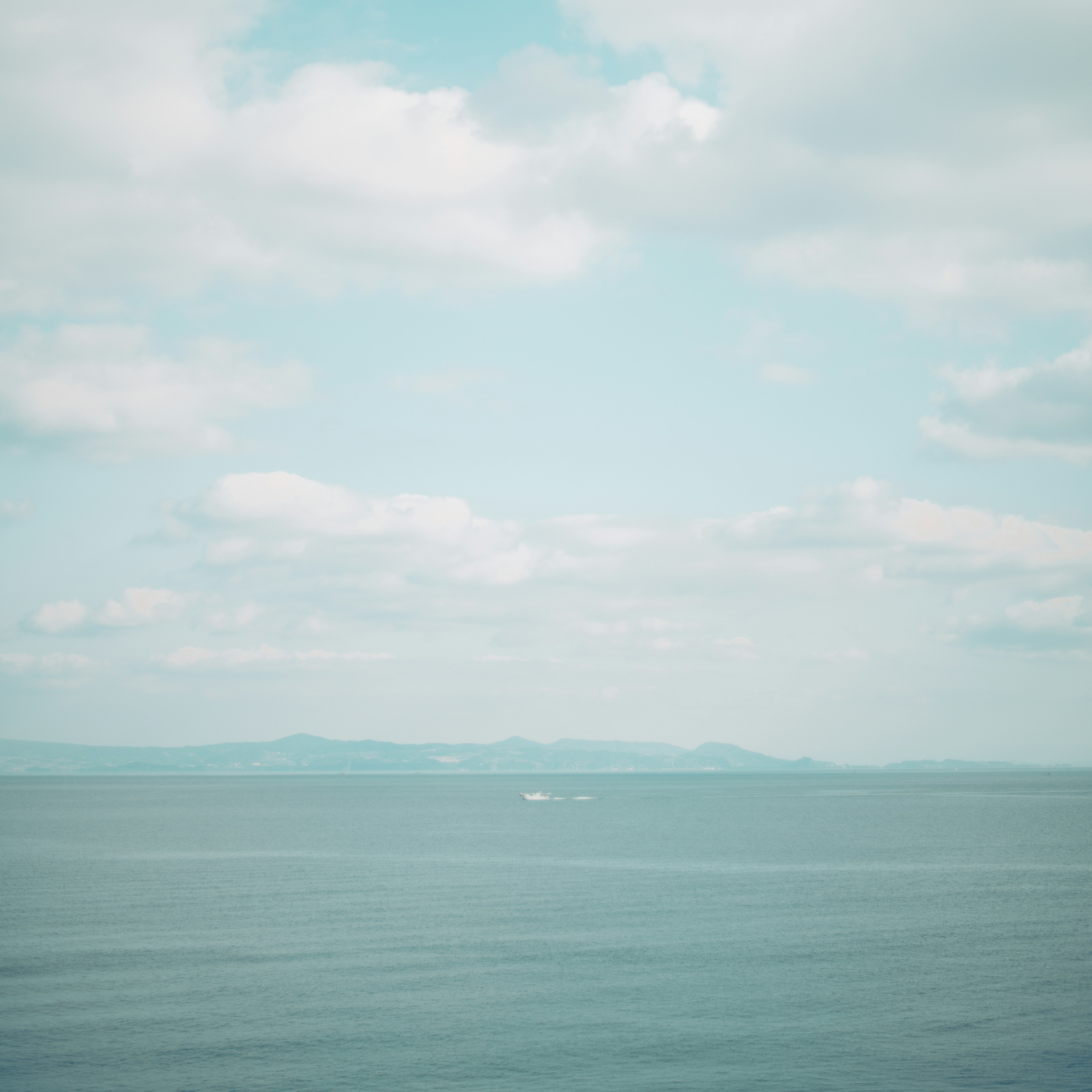 Laut biru tenang dengan langit luas penuh awan