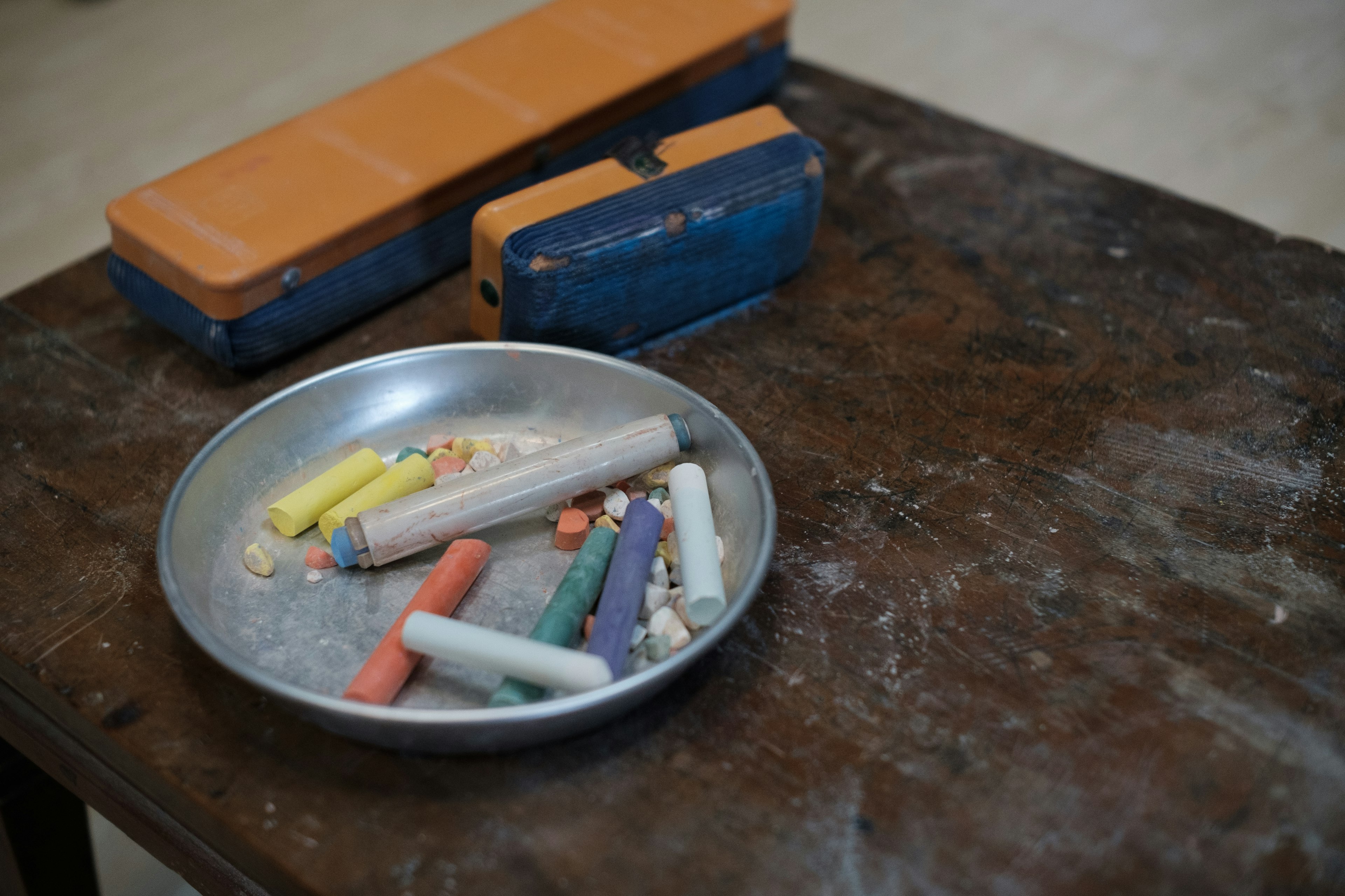 Colorful chalk pieces and an eraser on a plate on a wooden table