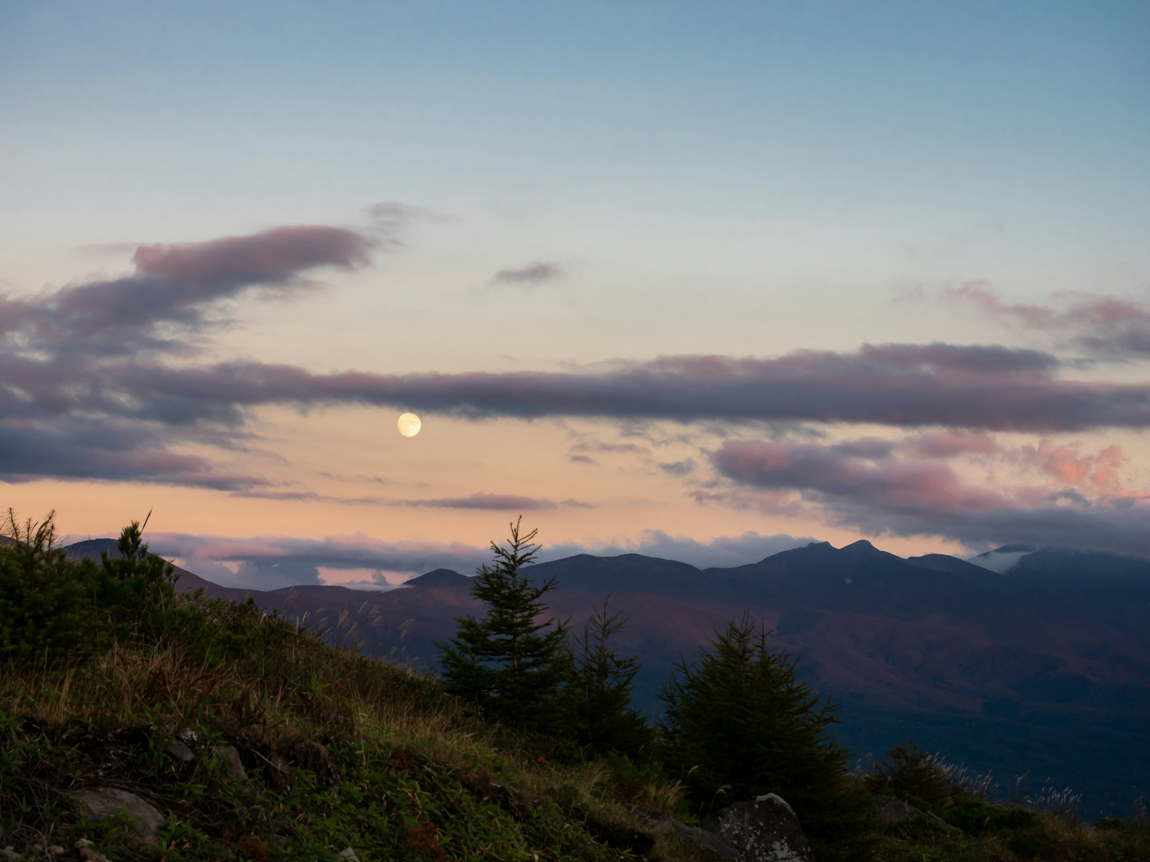 Vista escénica de montañas con una luna en el cielo crepuscular