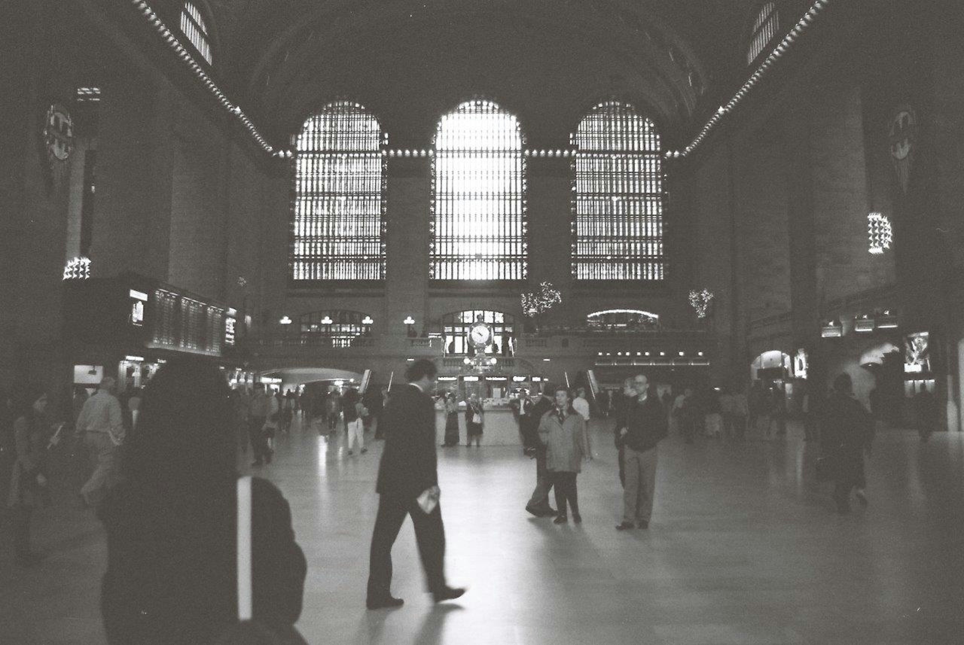 Foto en blanco y negro del interior de la estación Grand Central con una multitud animada y grandes ventanas que permiten la entrada de luz