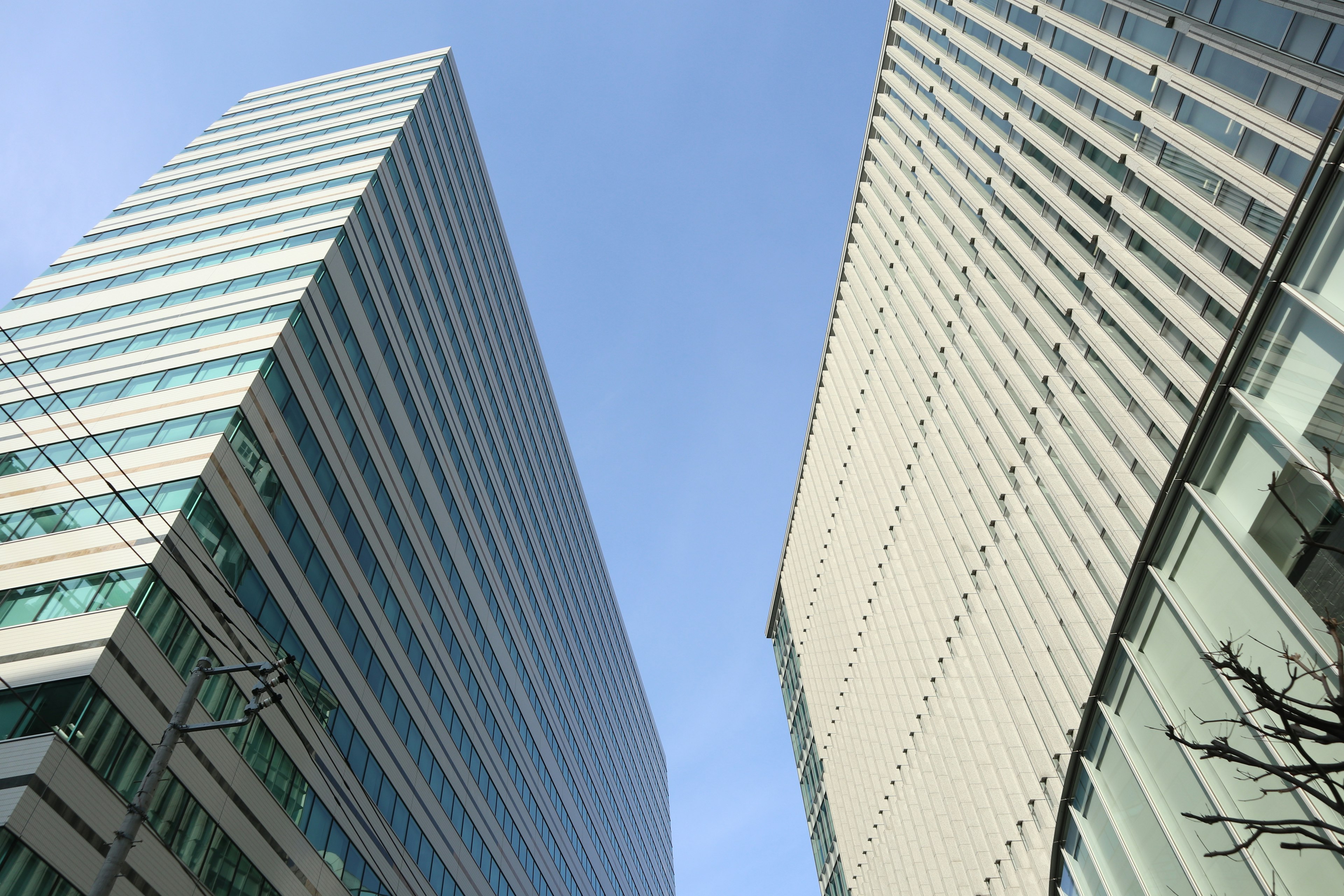 Dua gedung modern berdiri miring di bawah langit biru