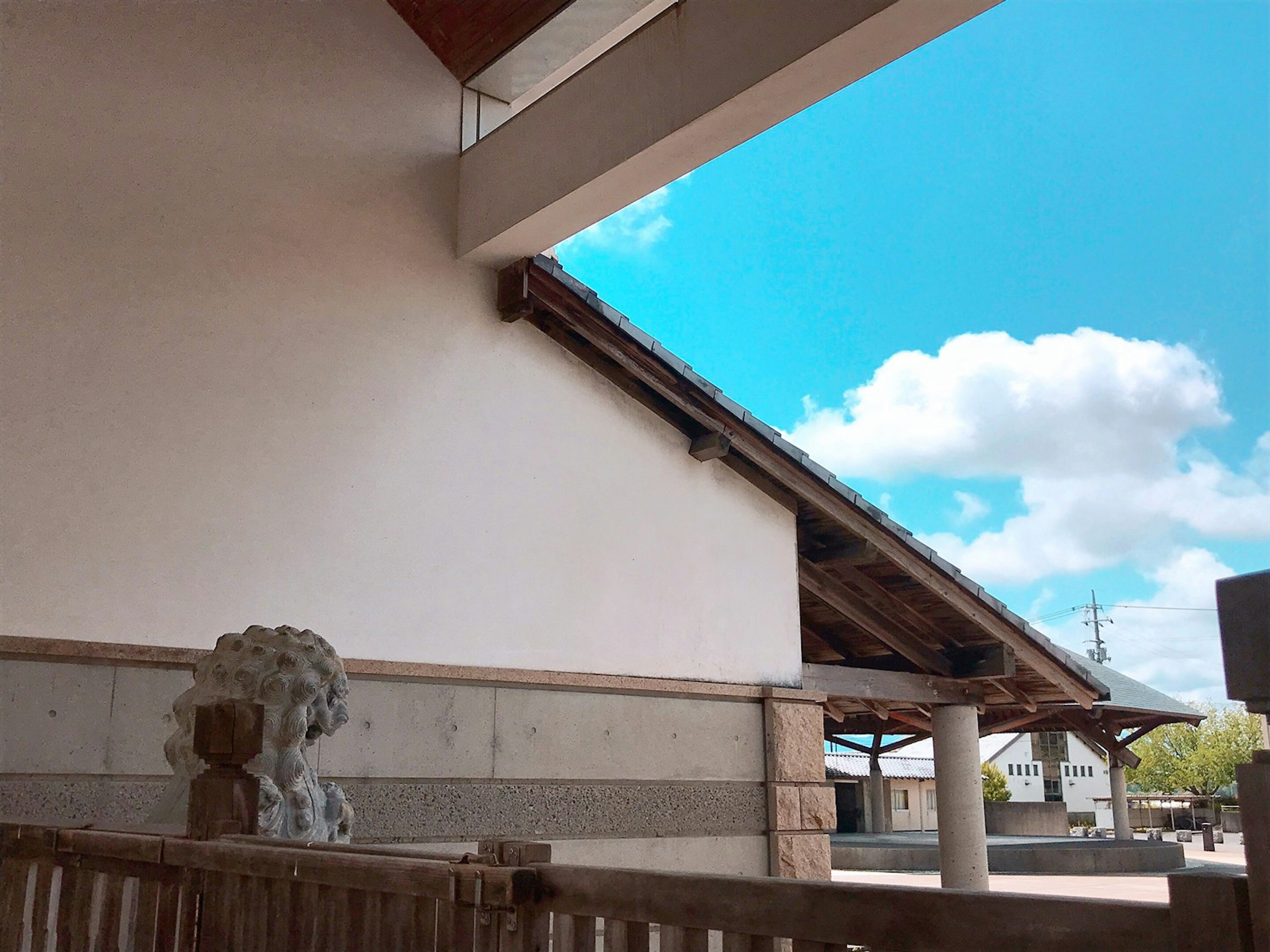 Side view of a traditional building with a stone lion statue under a blue sky