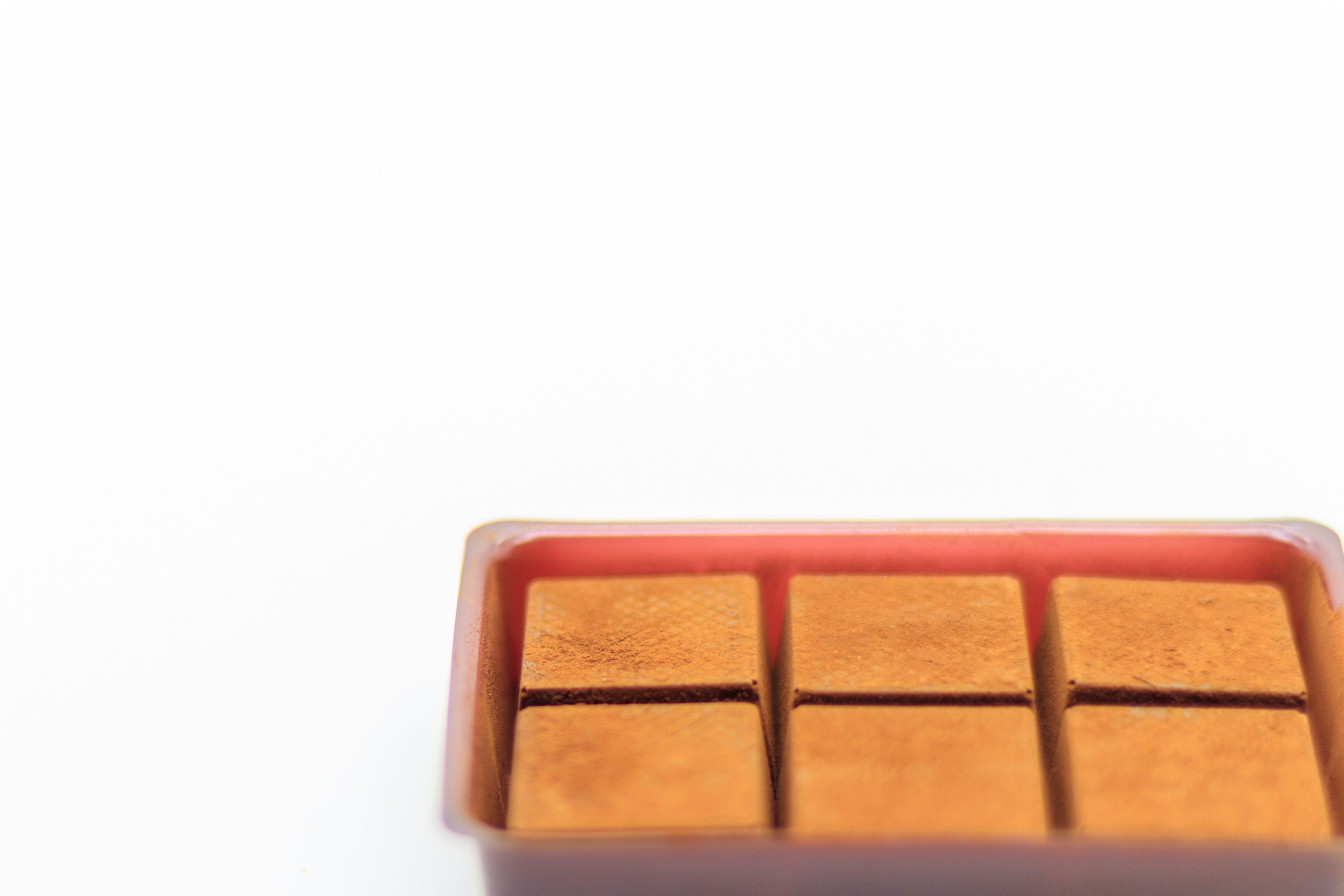 Brown square sweets arranged in a red tray