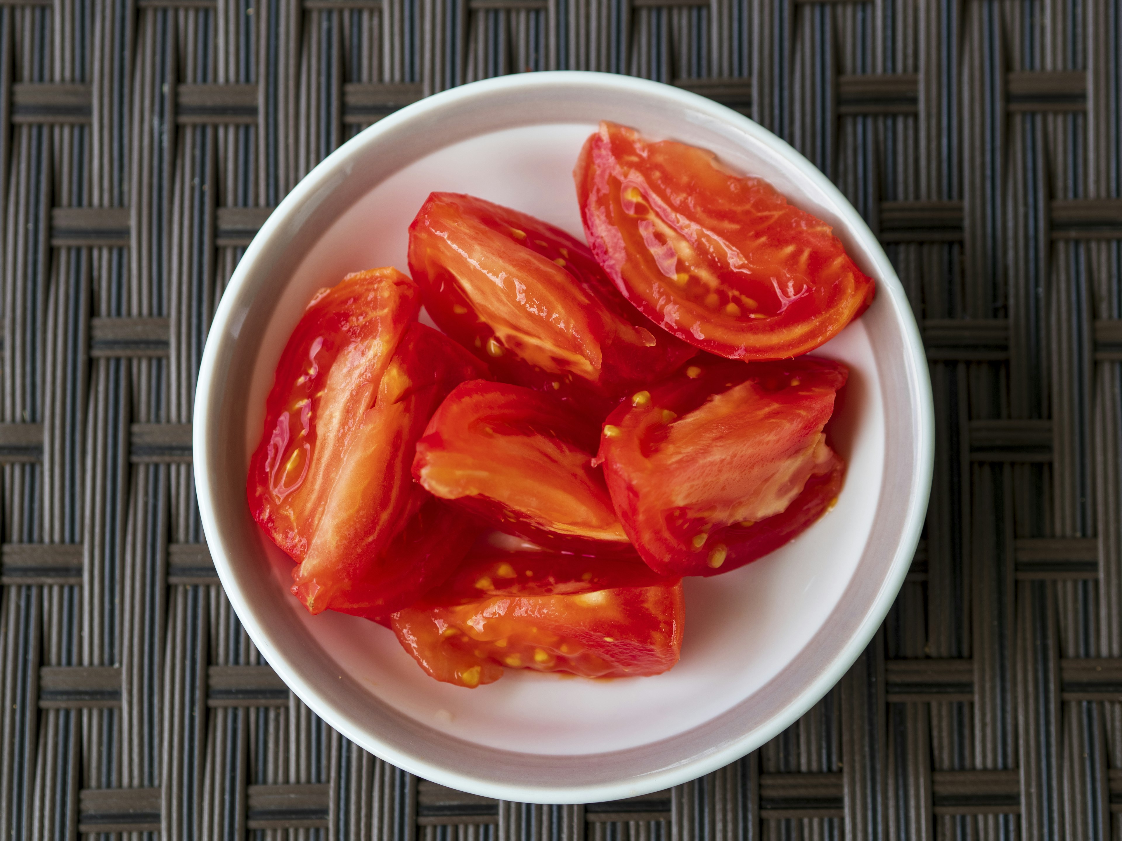 Fette di pomodoro rosso disposte in una ciotola bianca