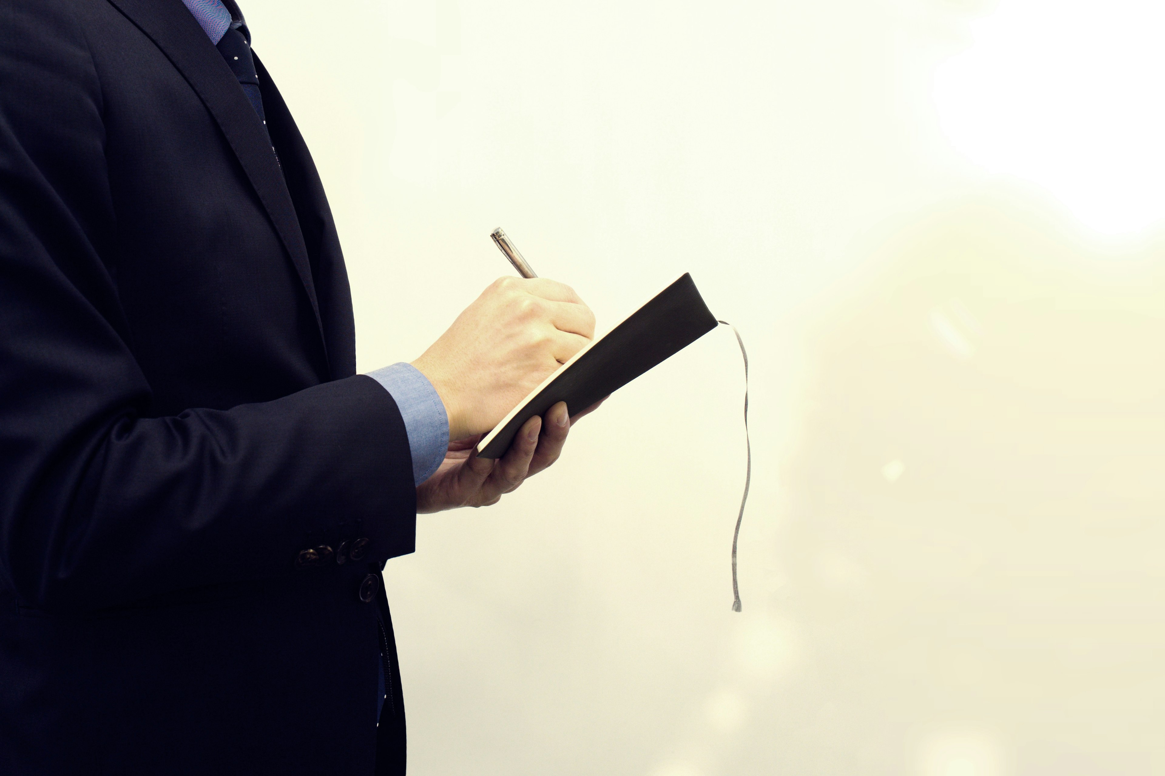 Un hombre con traje escribiendo notas en un cuaderno