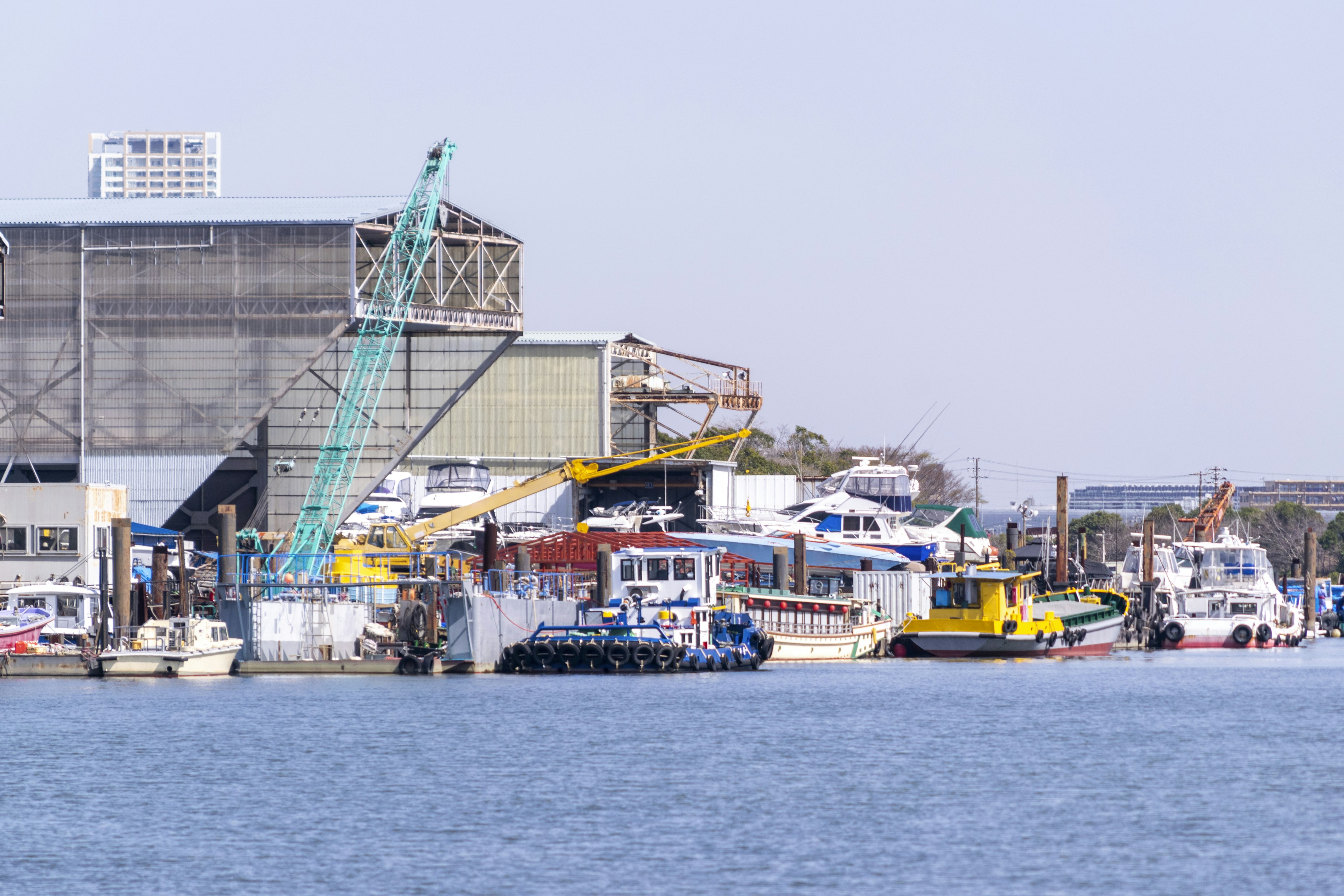 Harbor scene with moored boats and a crane