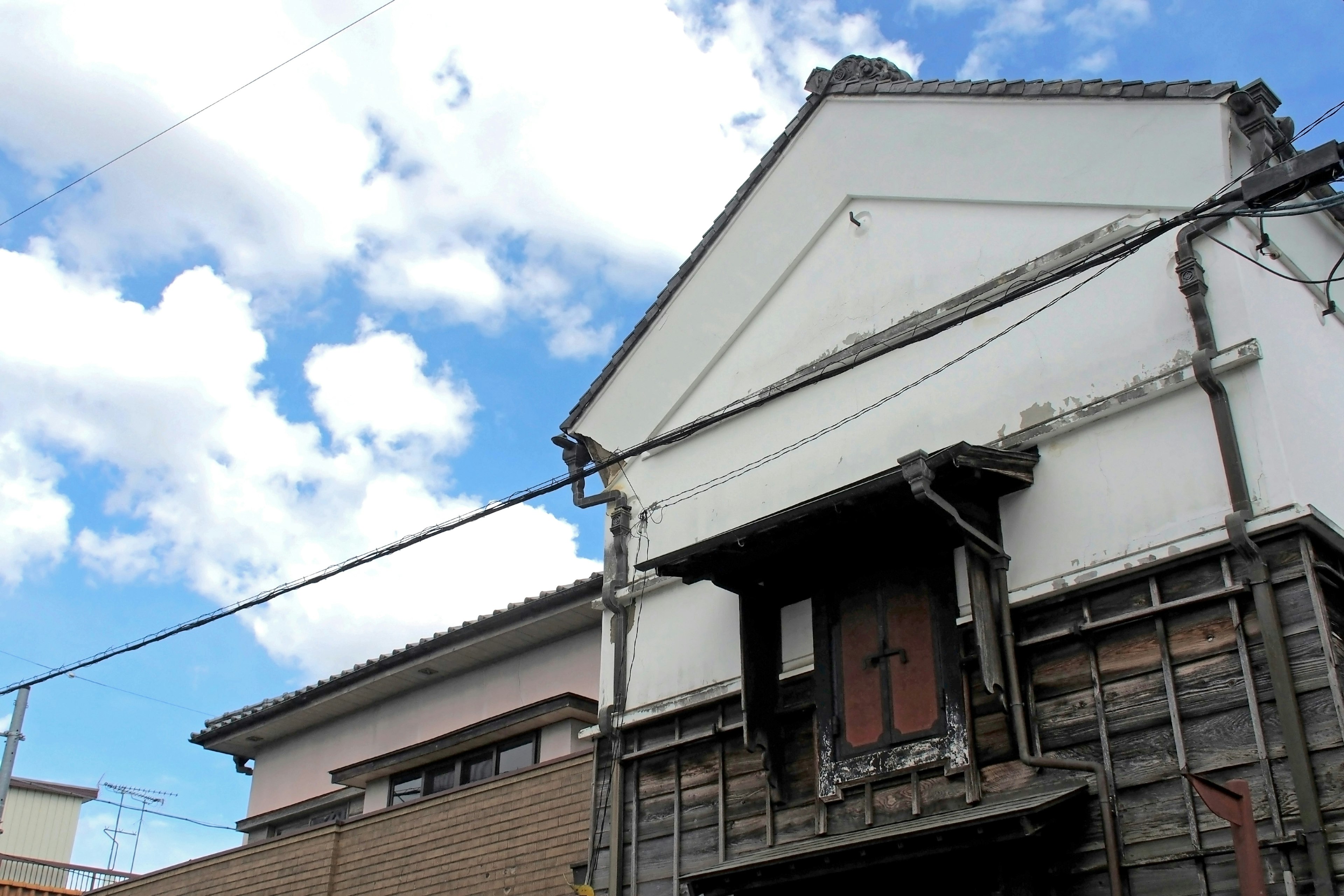 Partie d'un bâtiment traditionnel japonais avec une façade blanche et un toit distinctif