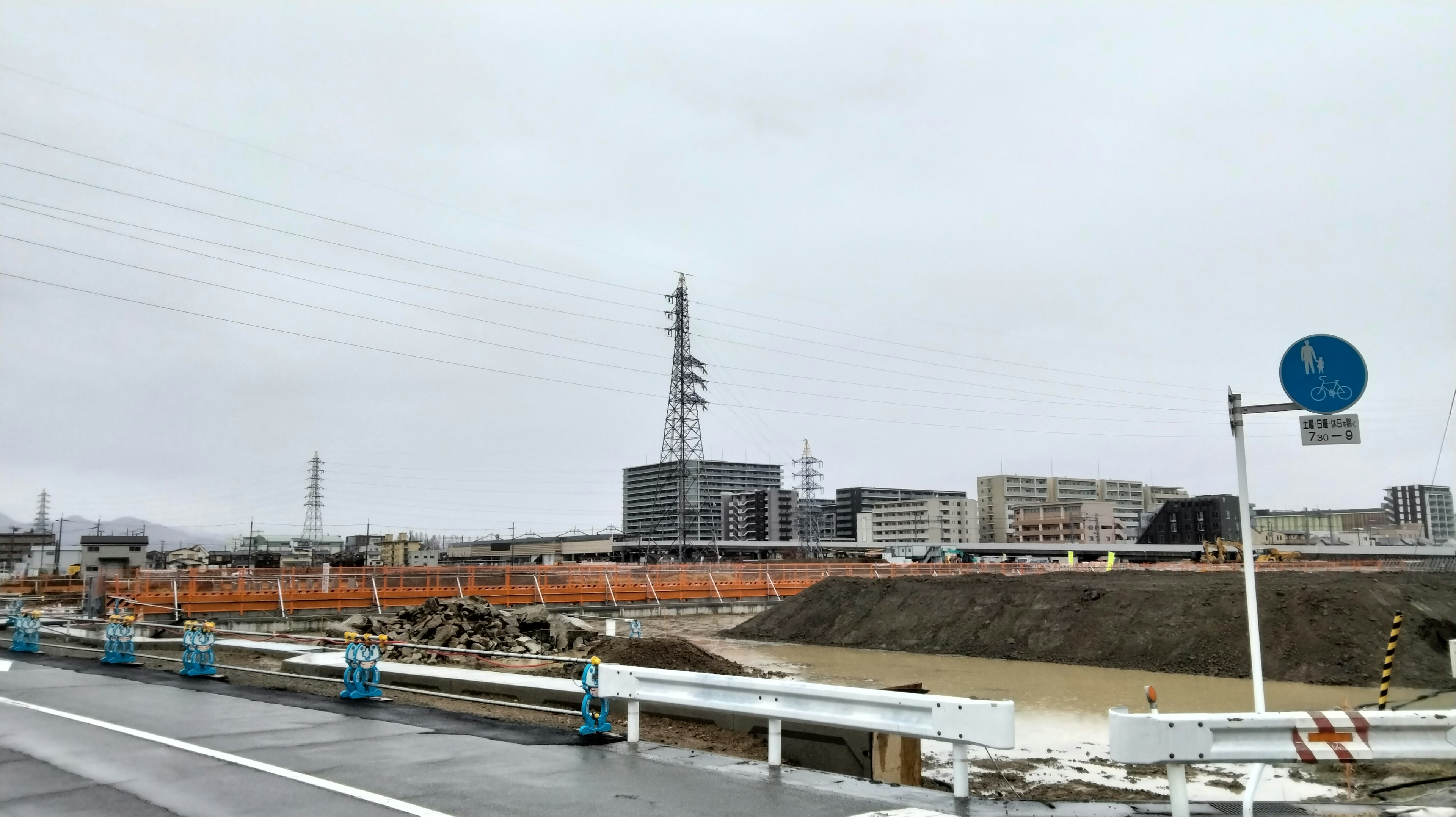 Paisaje que muestra un sitio de construcción con edificios bajo un cielo gris