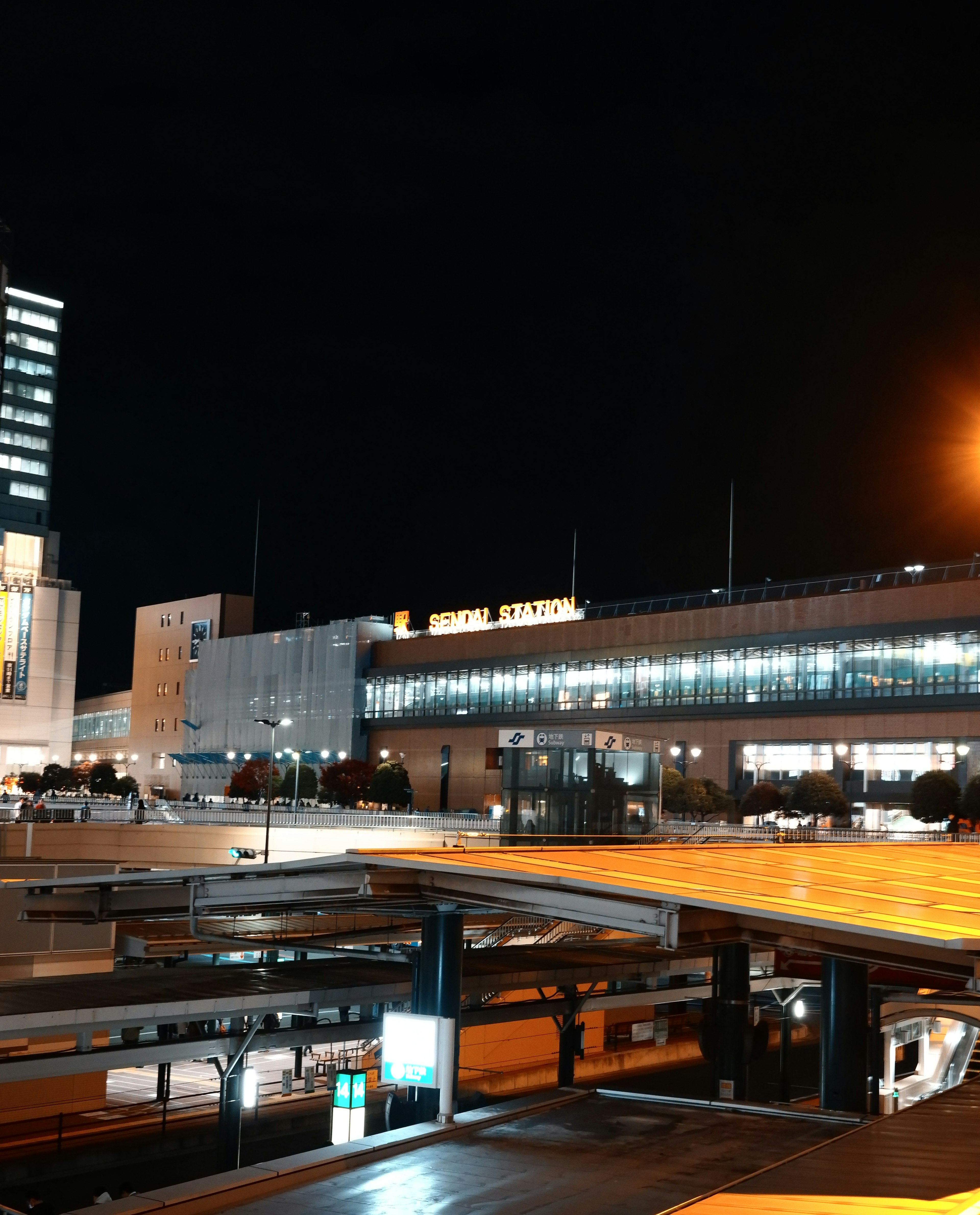 夜の駅の風景で明るい照明と交通の様子が見える