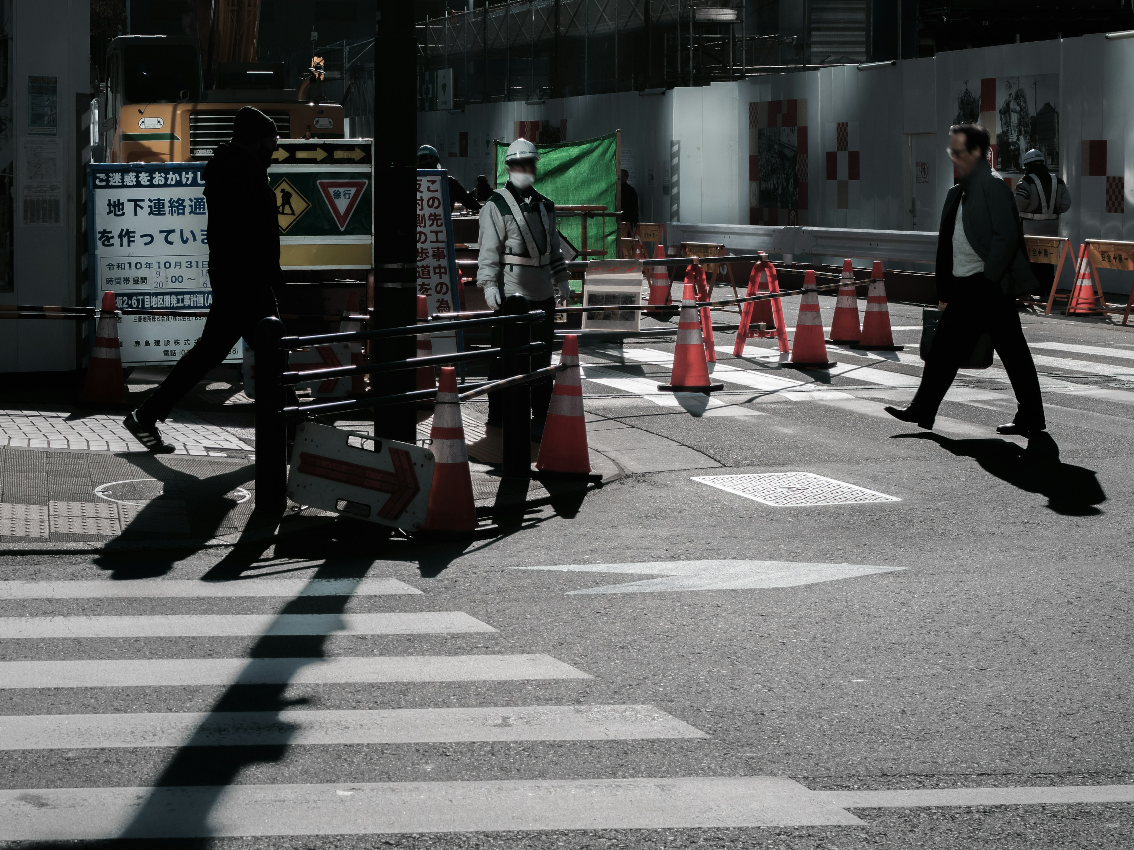 City scene with people crossing the intersection and traffic cones