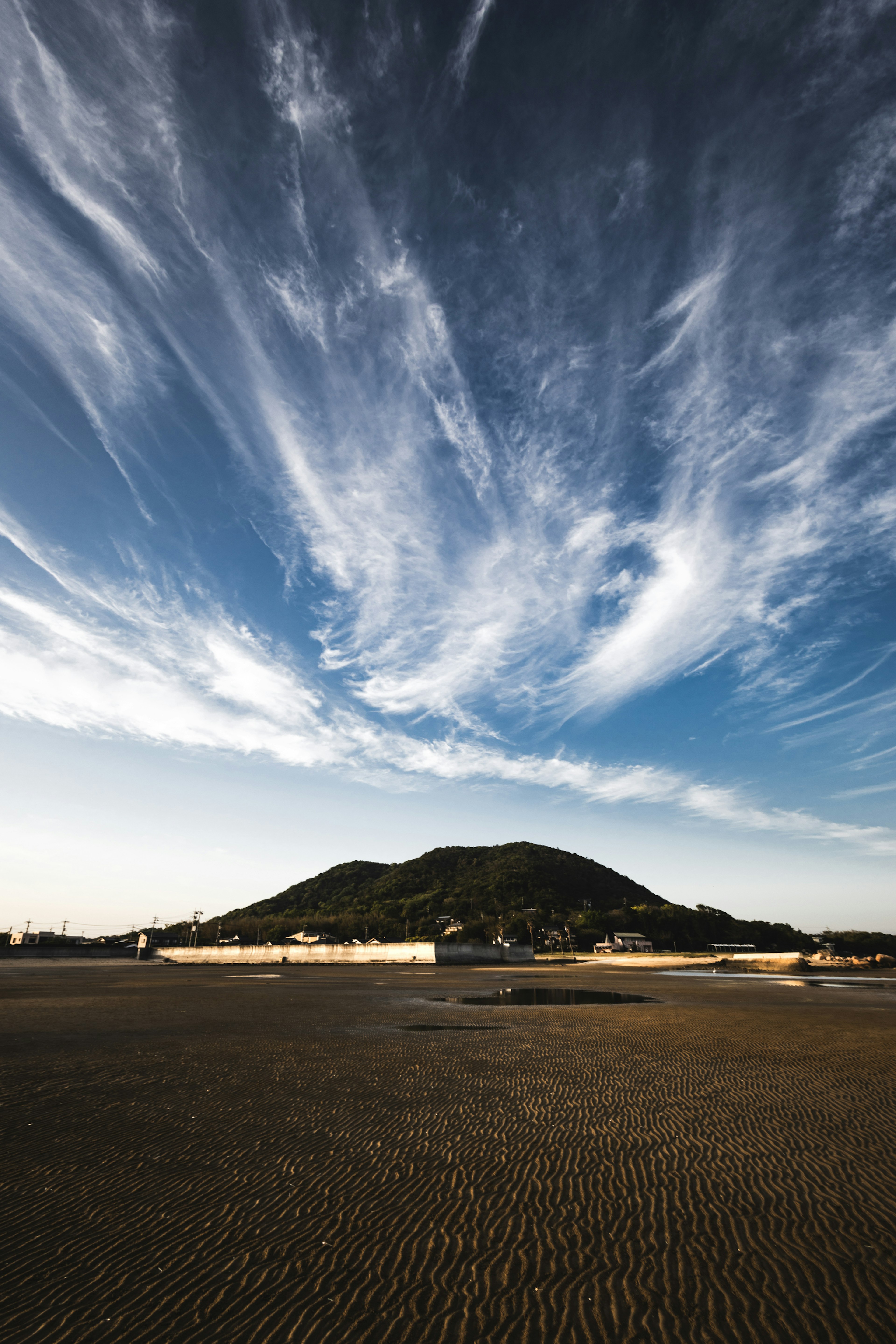 青空に白い雲が広がり、山が背景にある風景