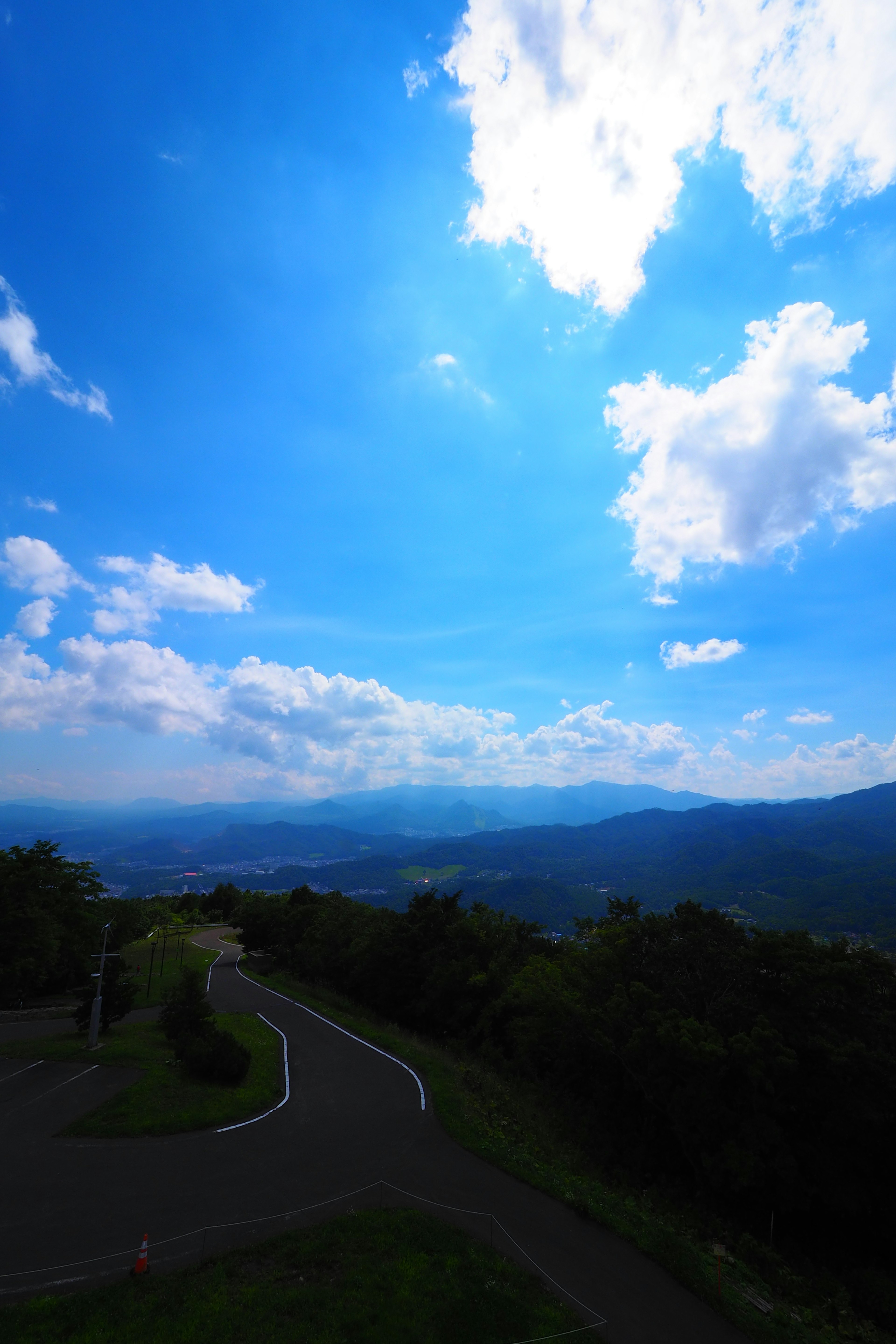 Pemandangan indah jalan berkelok di bawah langit biru cerah dengan awan putih