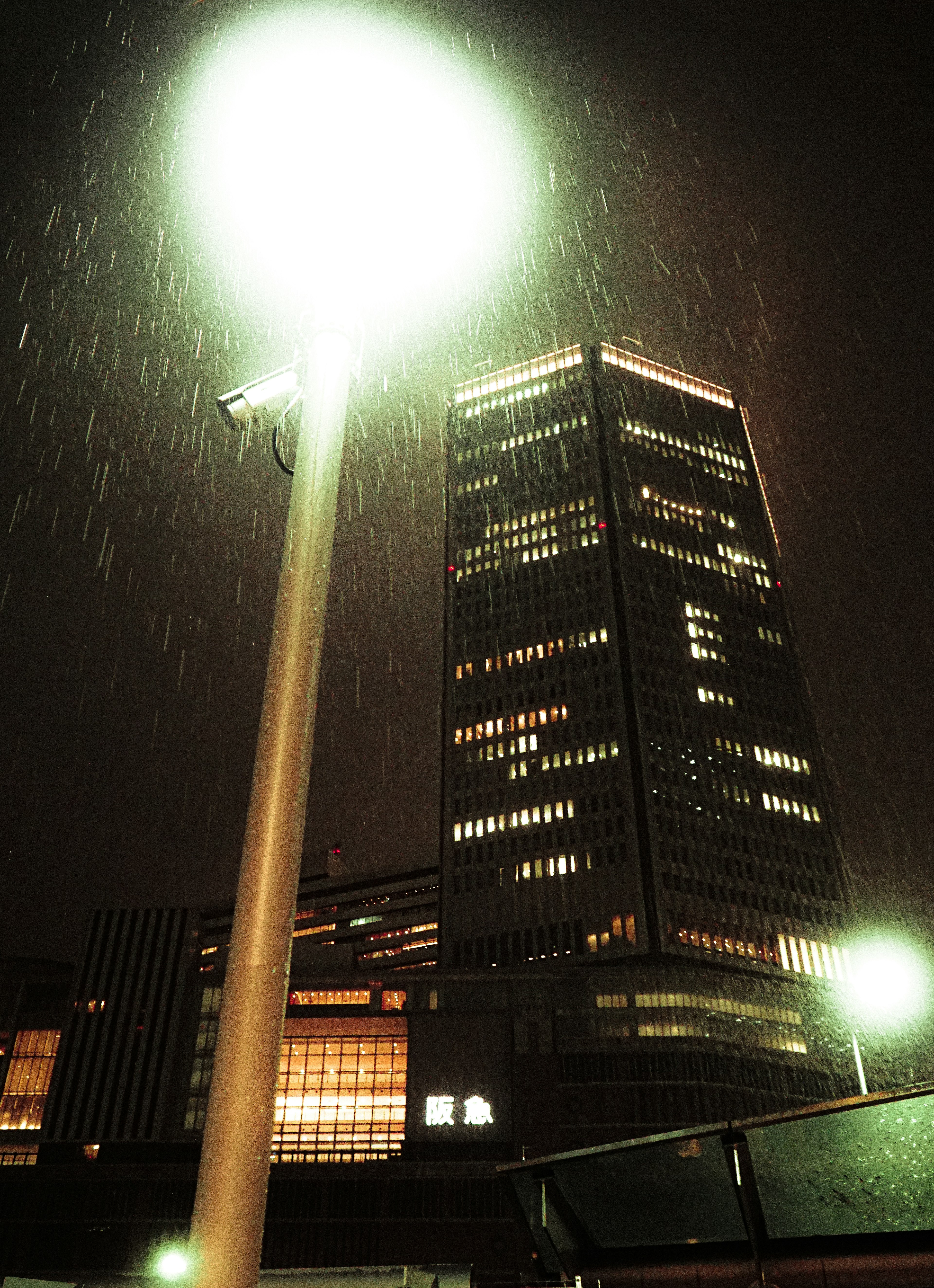 Städtische Szene mit einem beleuchteten Hochhaus in der Nacht und einer Straßenlaterne