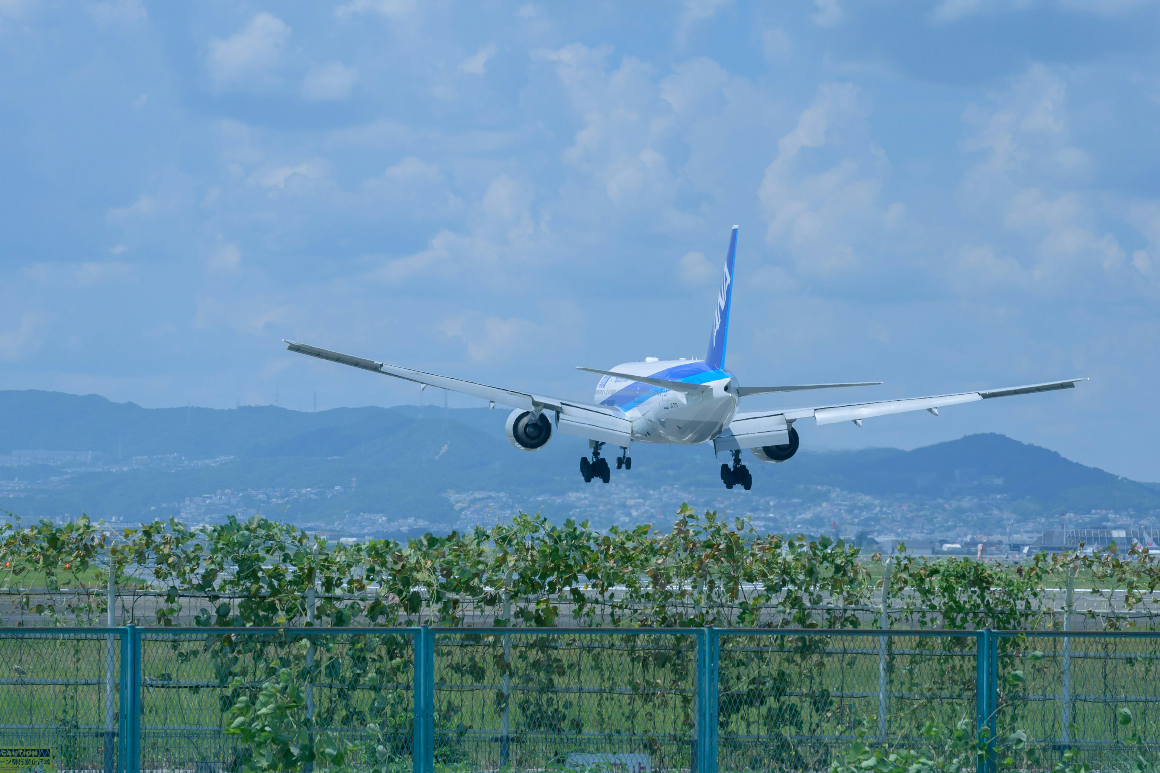 Passenger airplane landing against a blue sky with mountains in the background