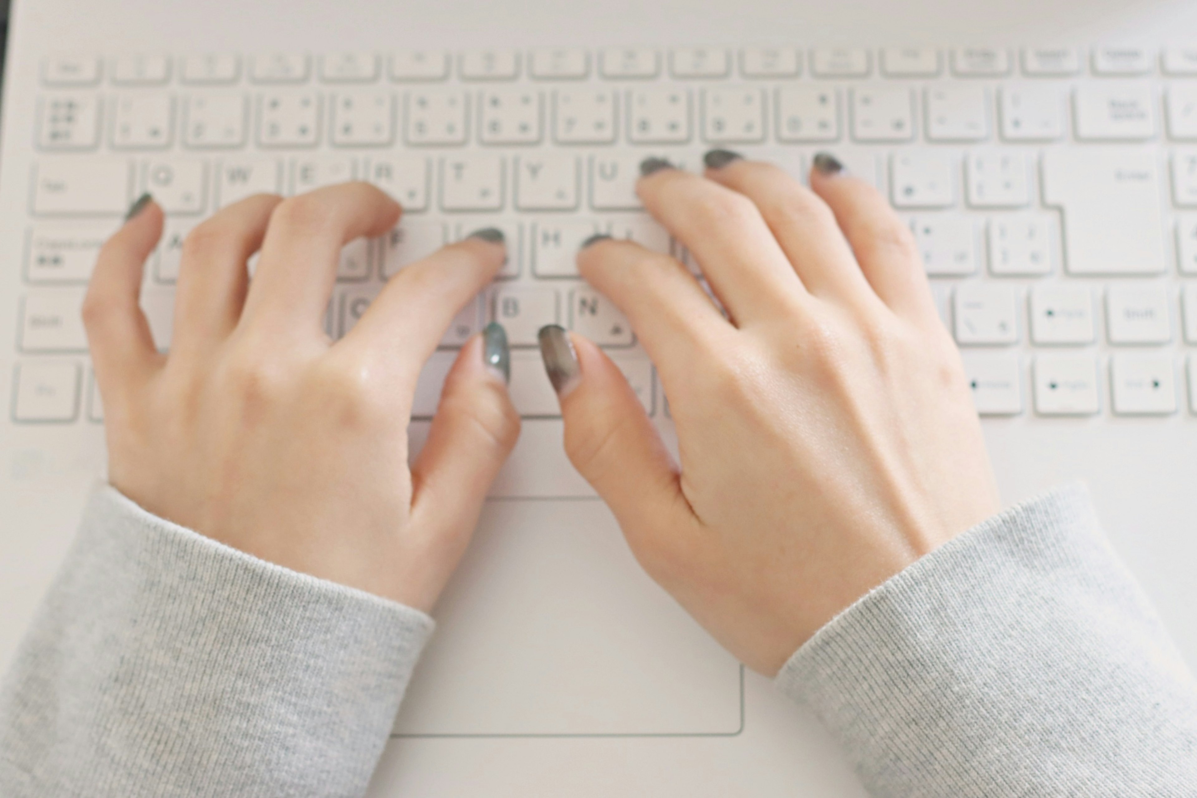 Hands typing on a white keyboard