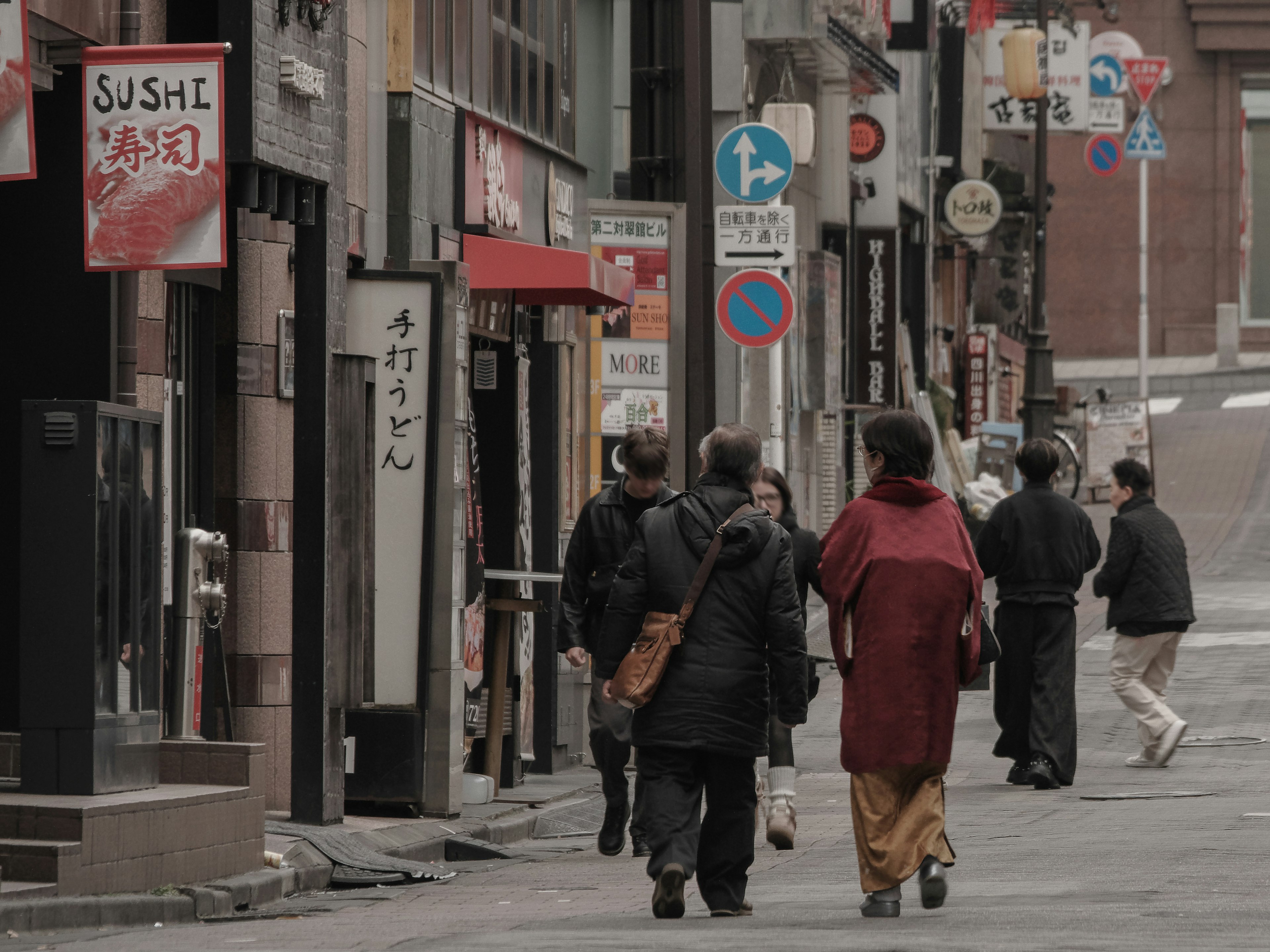 人们在城市街道上走，穿着和服的女性和穿黑色外套的人