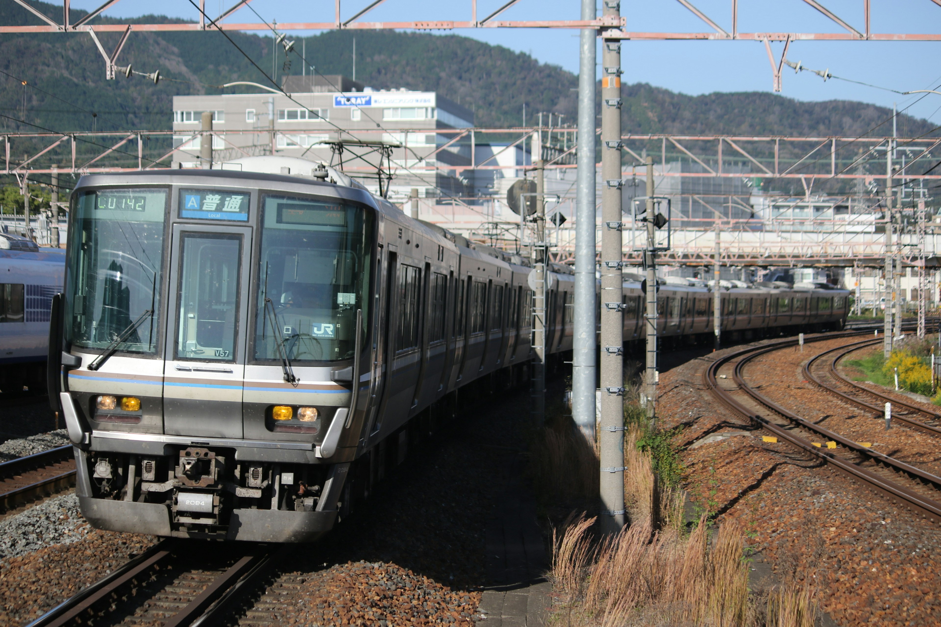 รถไฟญี่ปุ่นที่เลี้ยวโค้งพร้อมอาคารในเมืองด้านหลัง