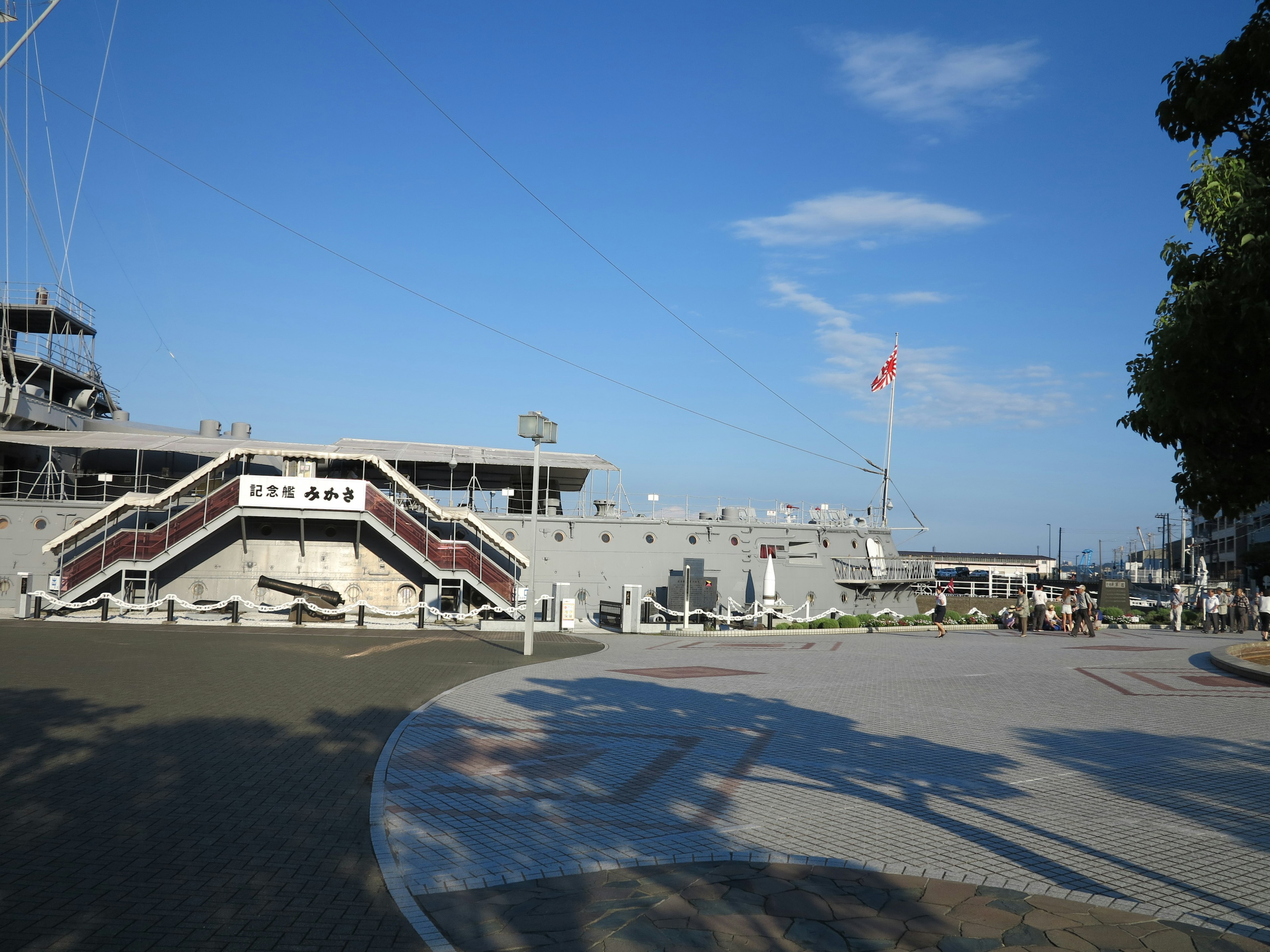 Harbor scene under blue sky featuring ship stairs and flag visible on the ship deck