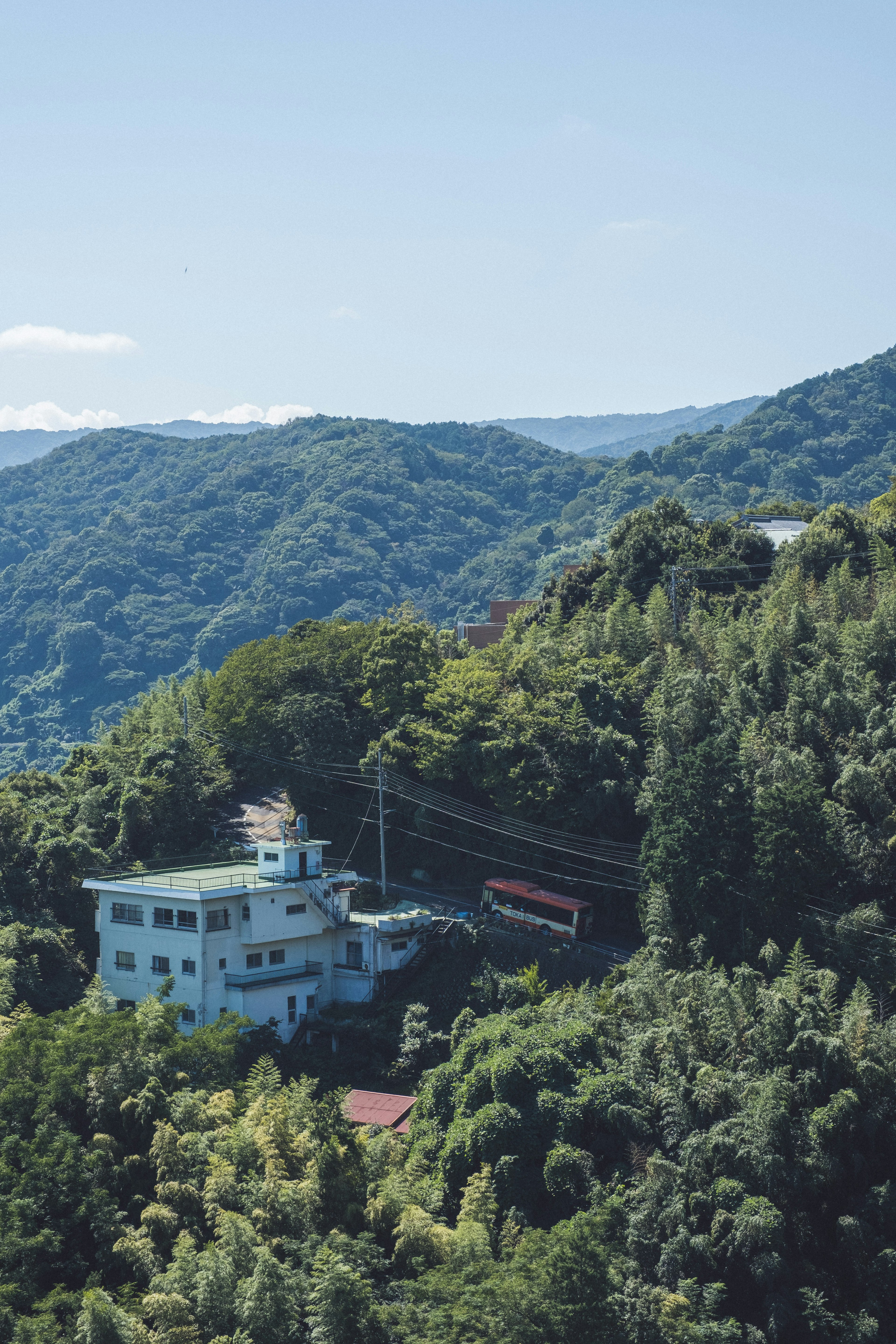 A blue building nestled in a green landscape with mountains