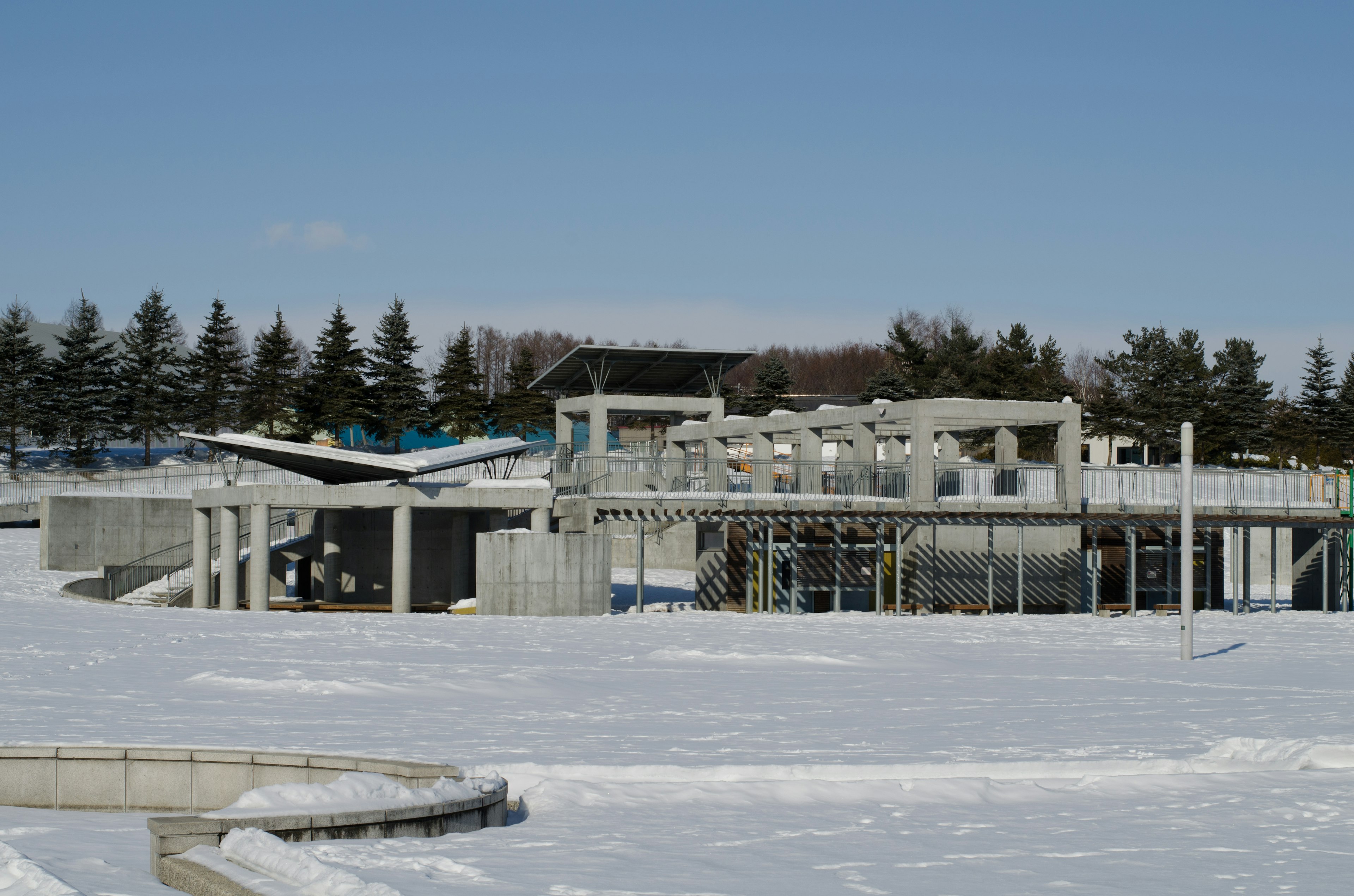 Construction site of a concrete structure covered in snow with a clear blue sky