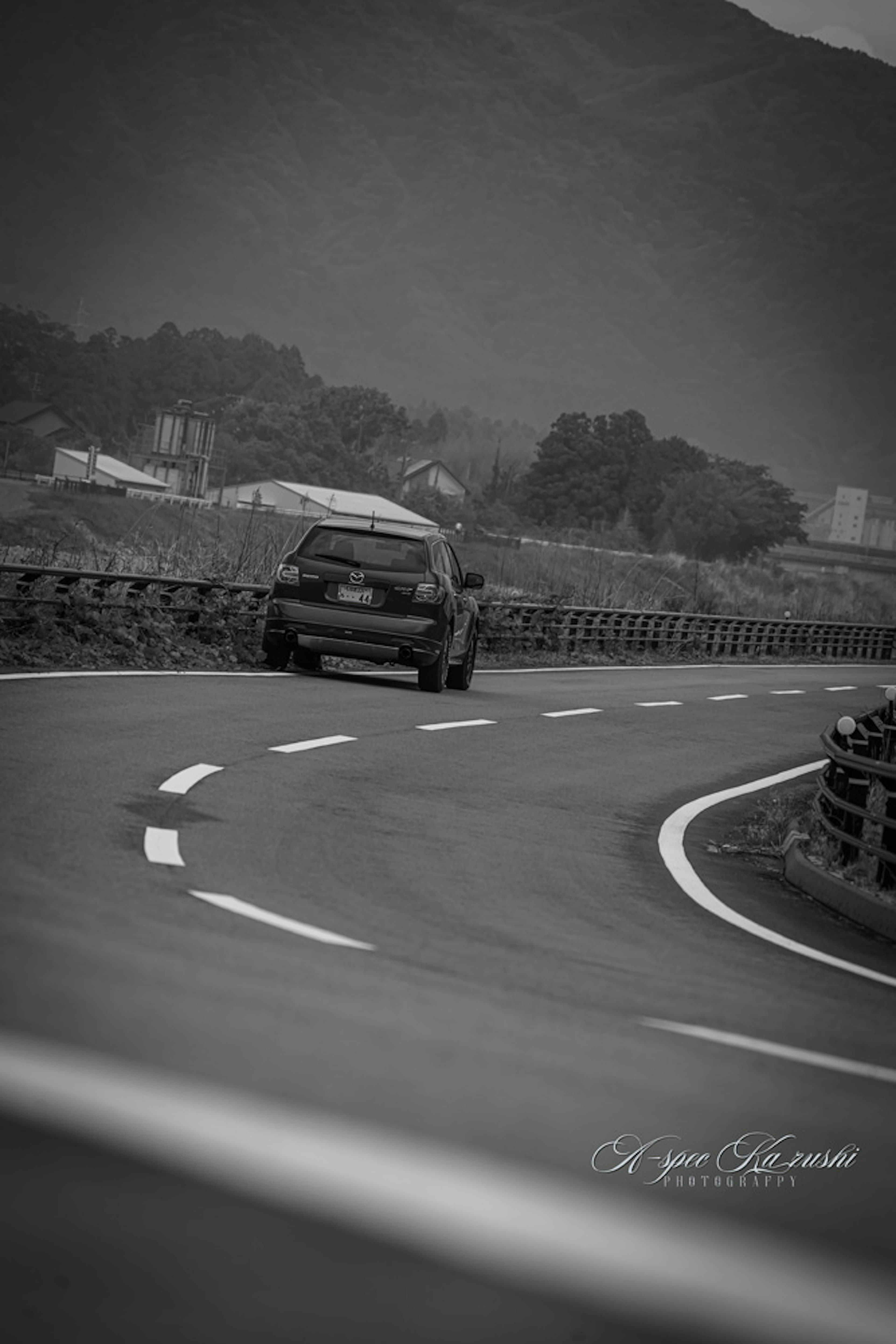 曲がりくねった道路を走る黒白の車と山の背景