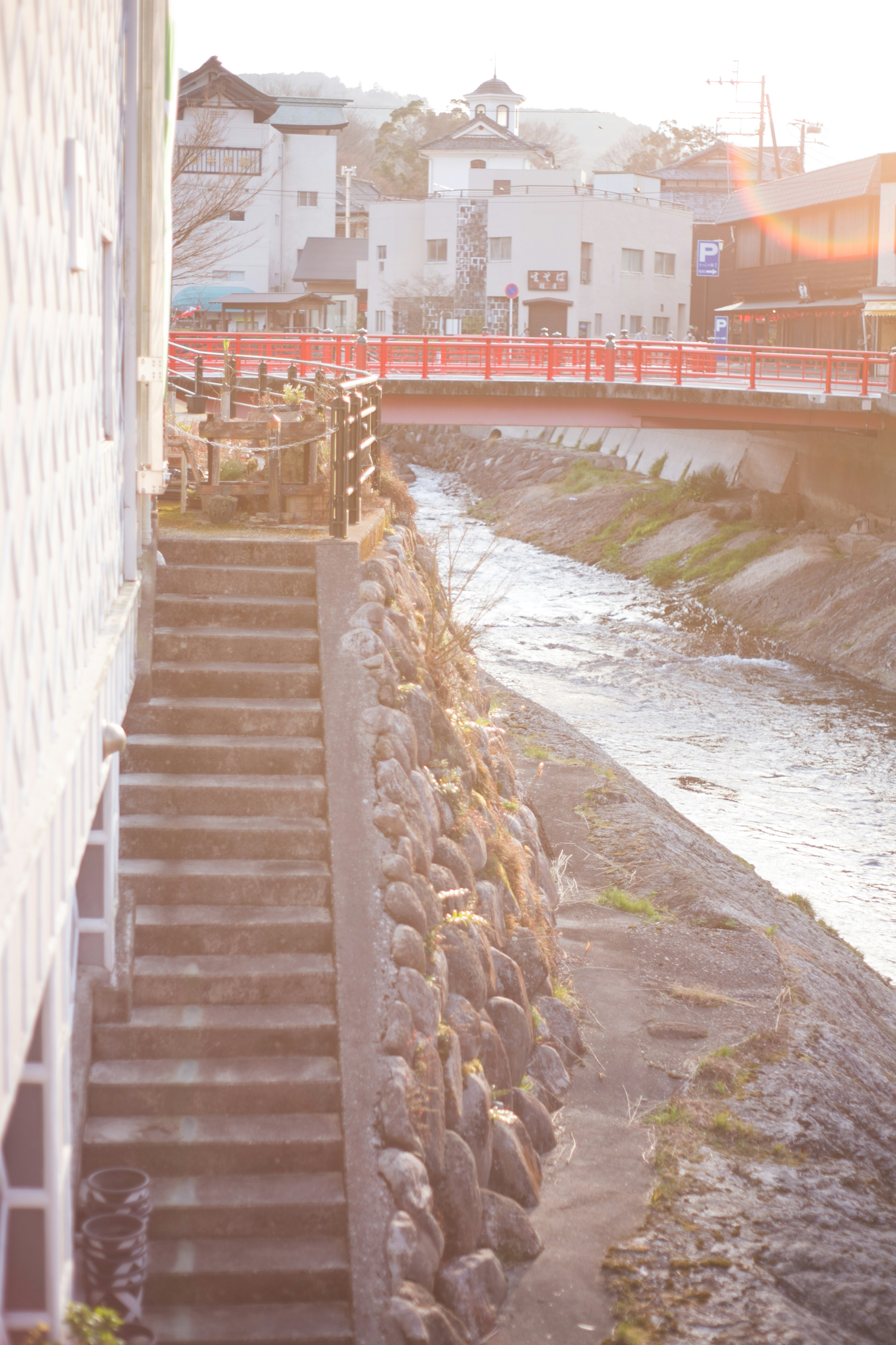 川沿いの階段と赤い橋が見える風景