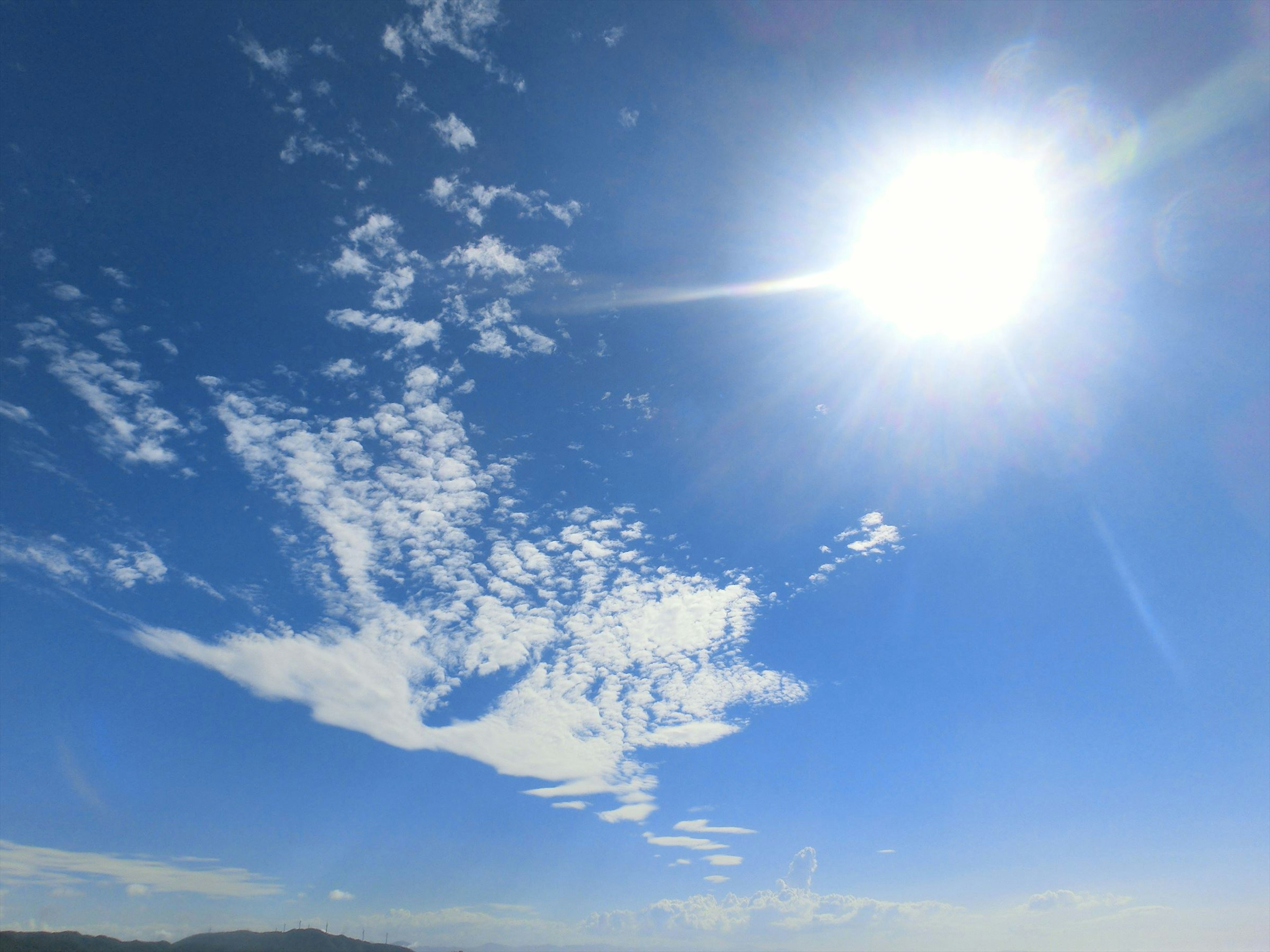 Helle Sonne scheint über einem klaren blauen Himmel mit verstreuten Wolken