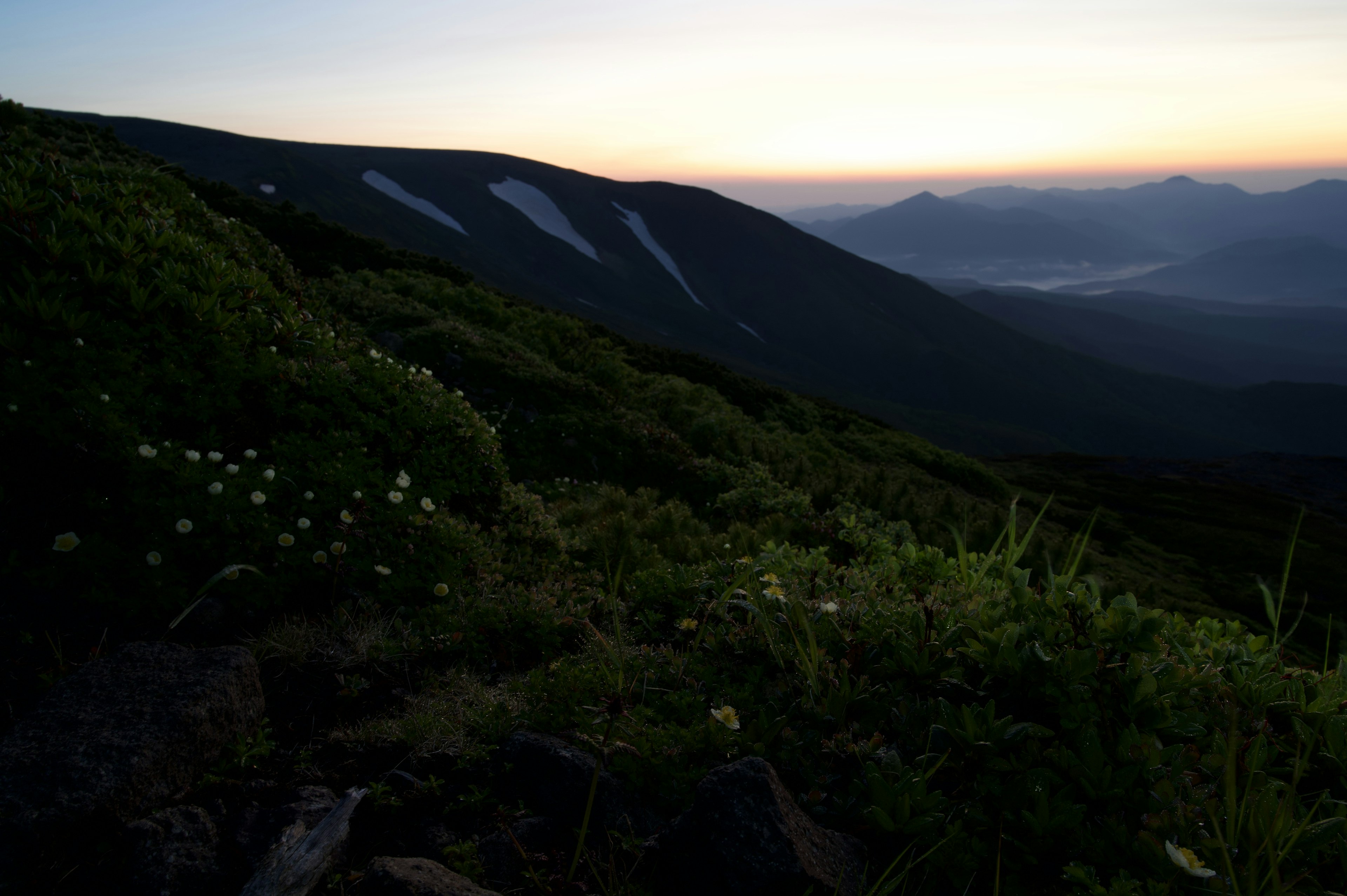 ทิวทัศน์ภูเขาที่สวยงามในยามพลบค่ำพร้อมความเขียวขจีและภูเขาไกล