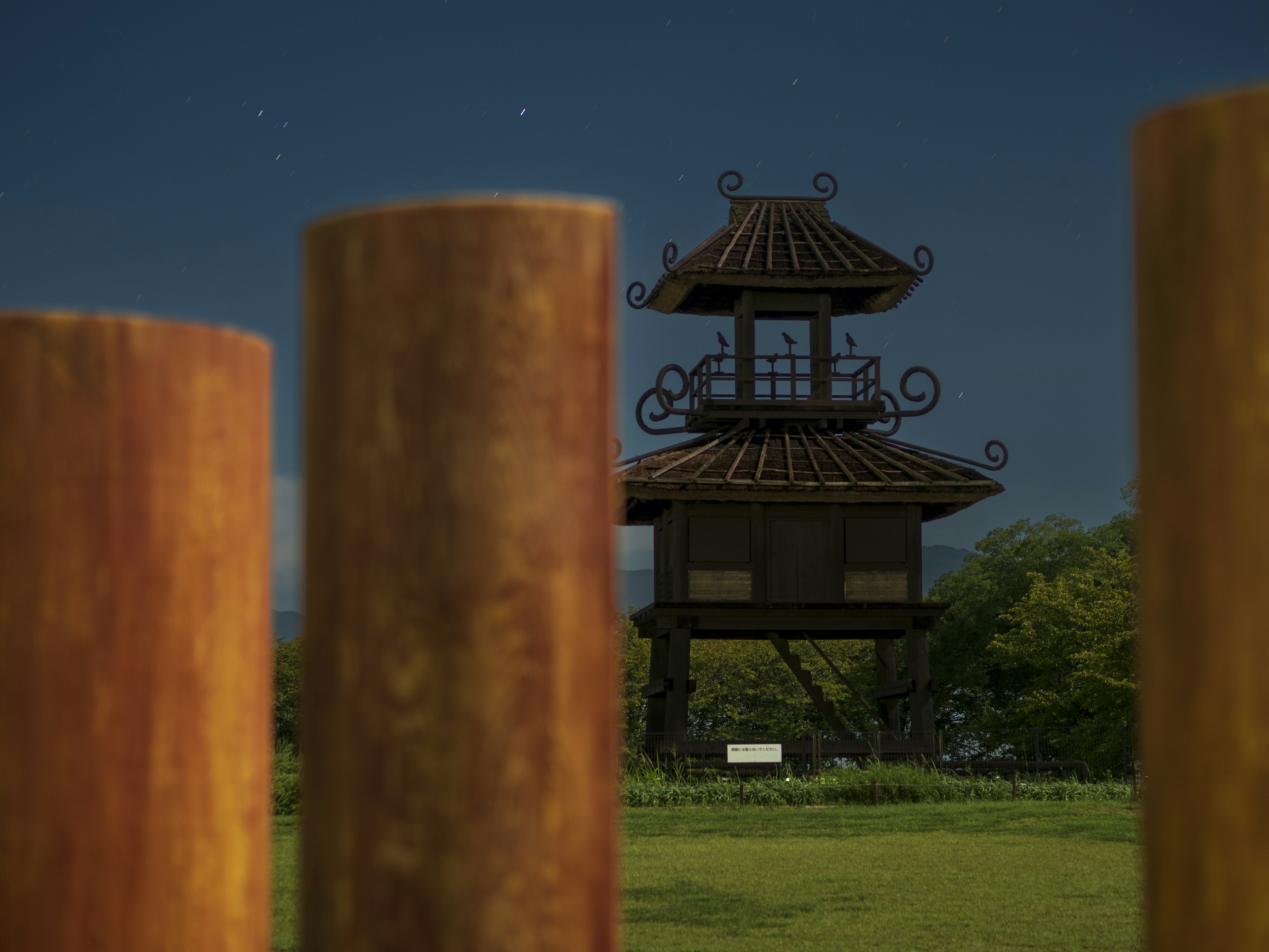 A beautiful tower under the night sky with wooden pillars in the foreground