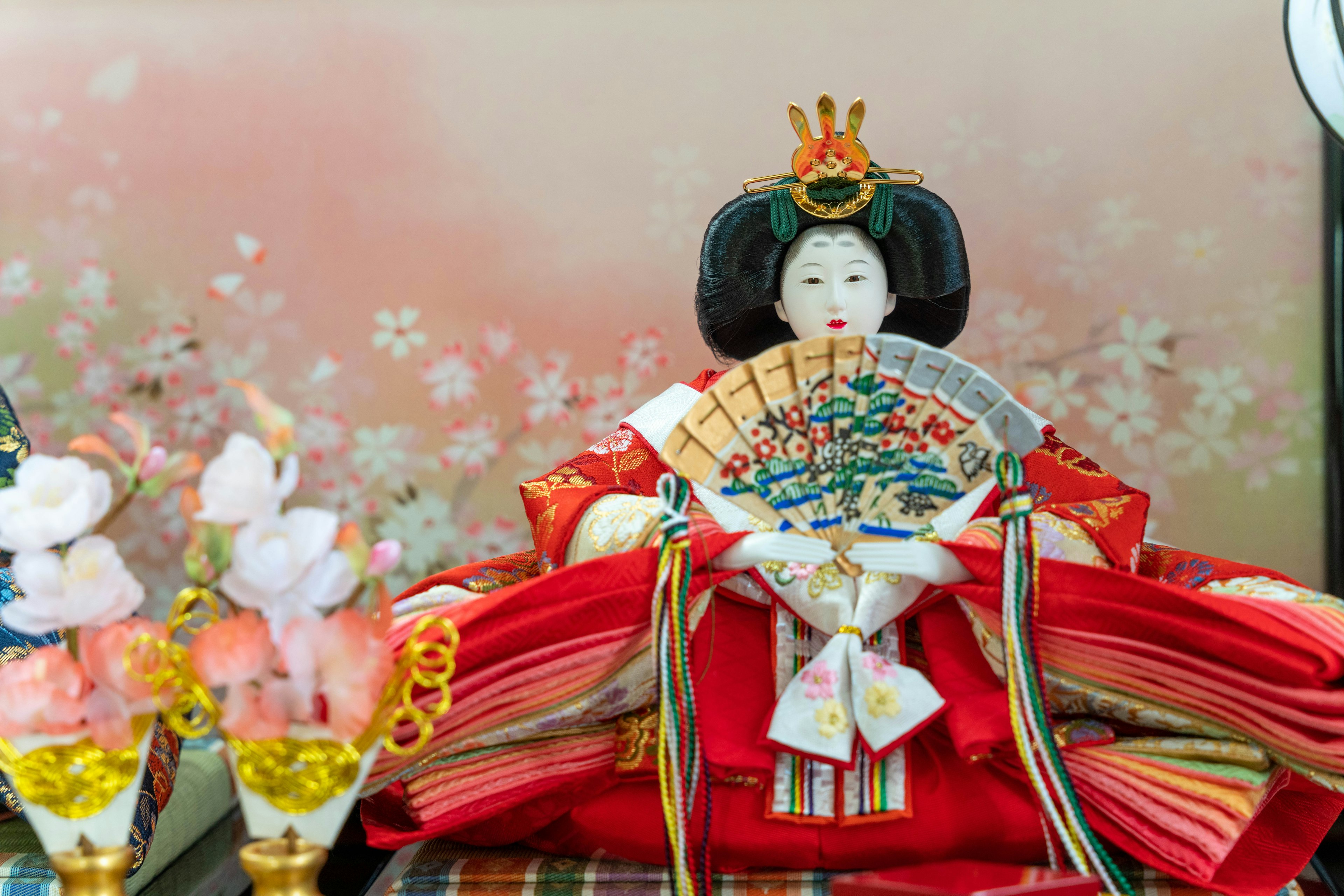 Beautiful Hina doll dressed in red for Hinamatsuri with a fan