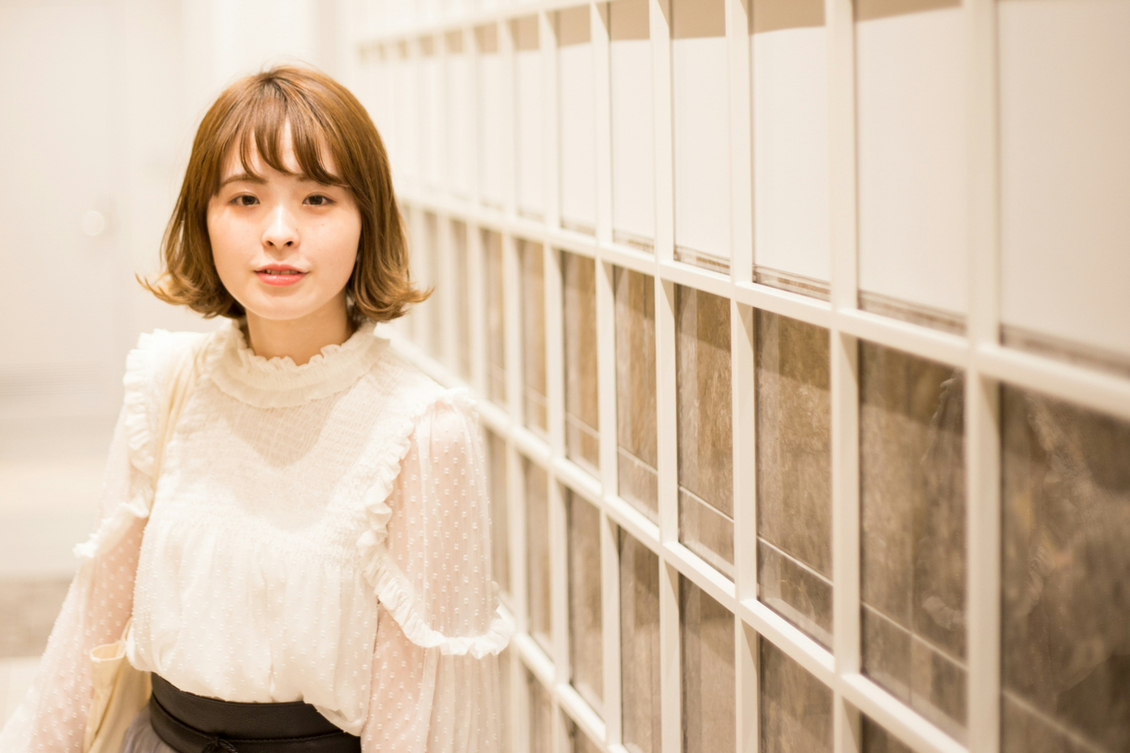 A woman in a white blouse stands in a bright corridor