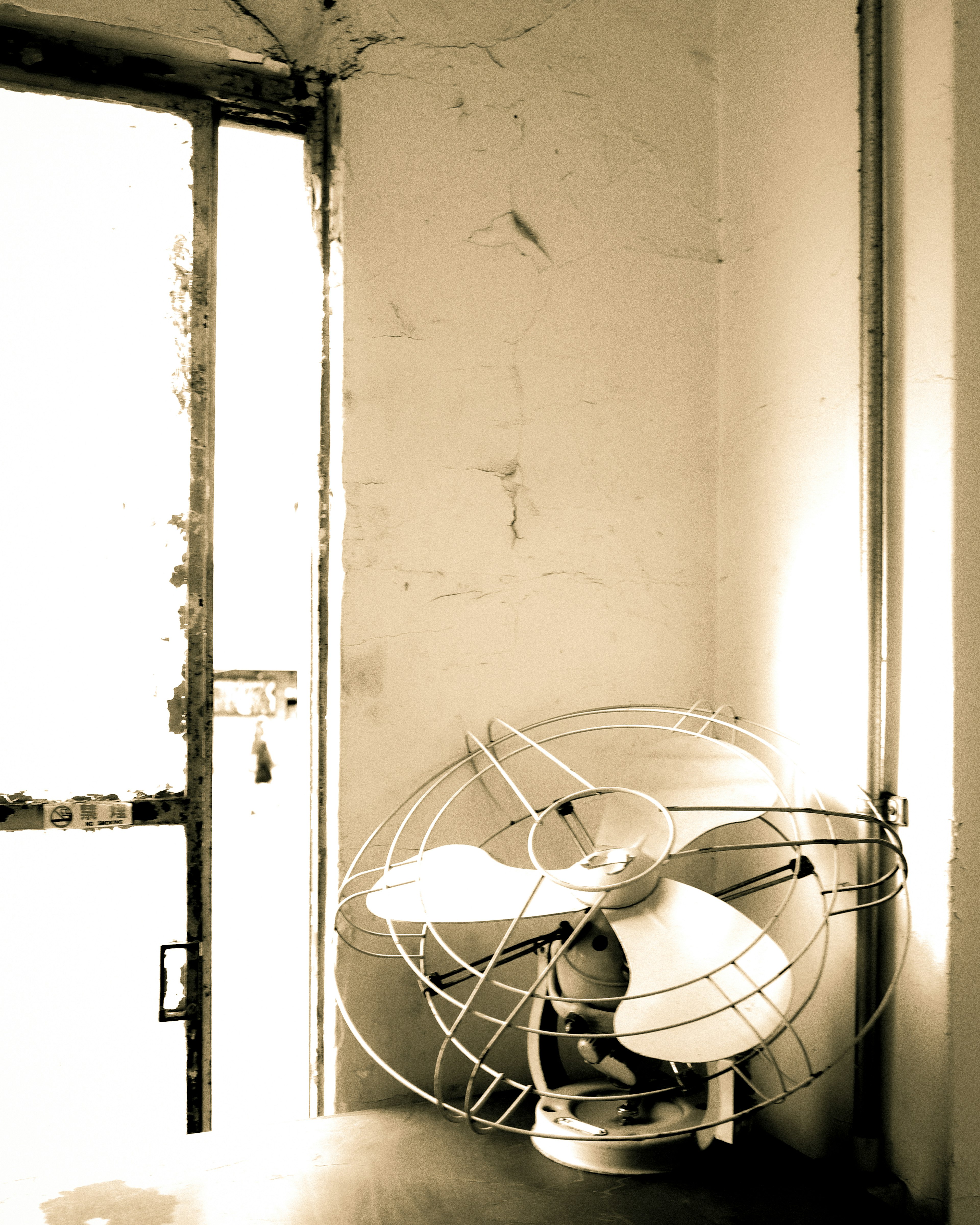 Esquina de una habitación con un ventilador viejo y una puerta abierta