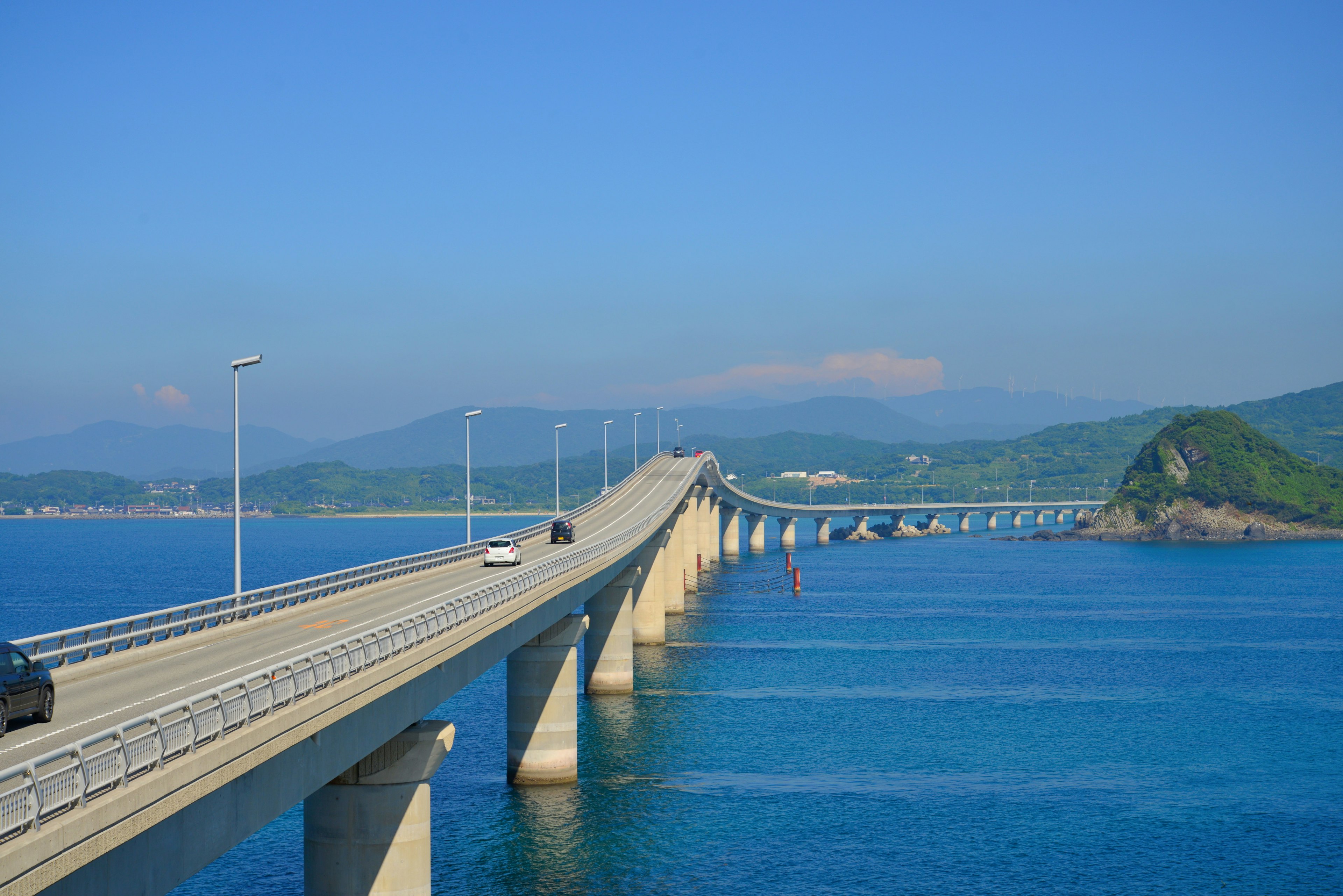 Eine lange Brücke über ein blaues Meer mit fahrenden Autos