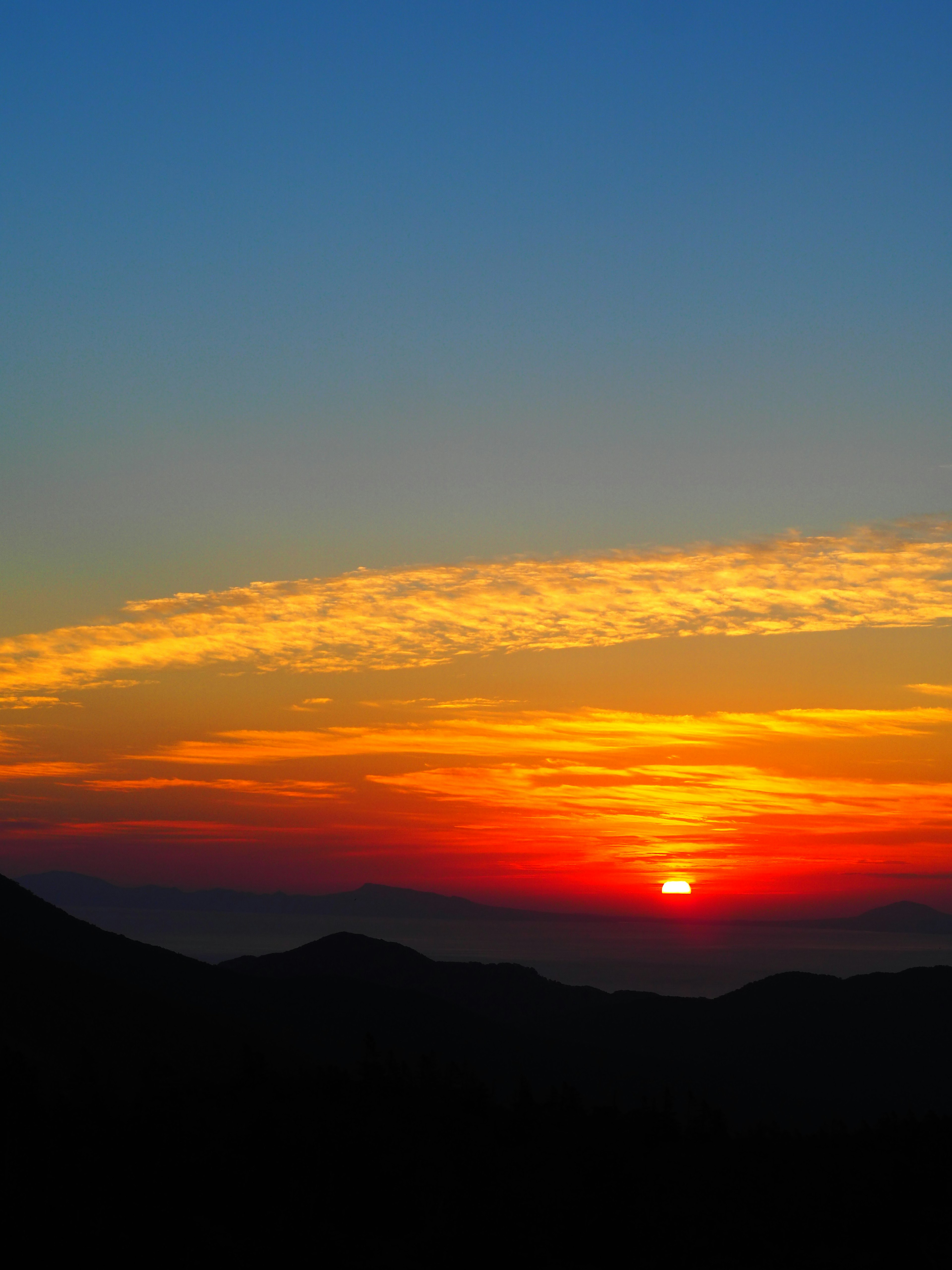 Schöner Sonnenuntergangshimmel mit Silhouetten von Bergen