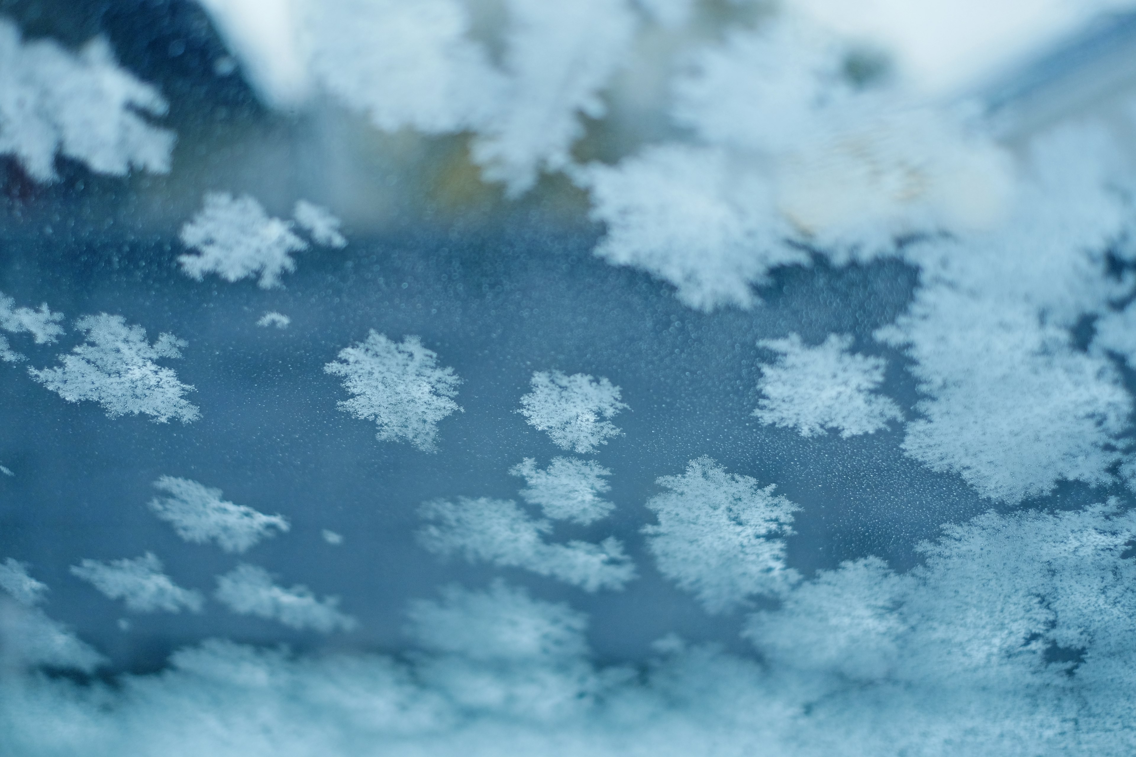 Ventana helada con patrones intrincados de copos de nieve sobre un fondo azul