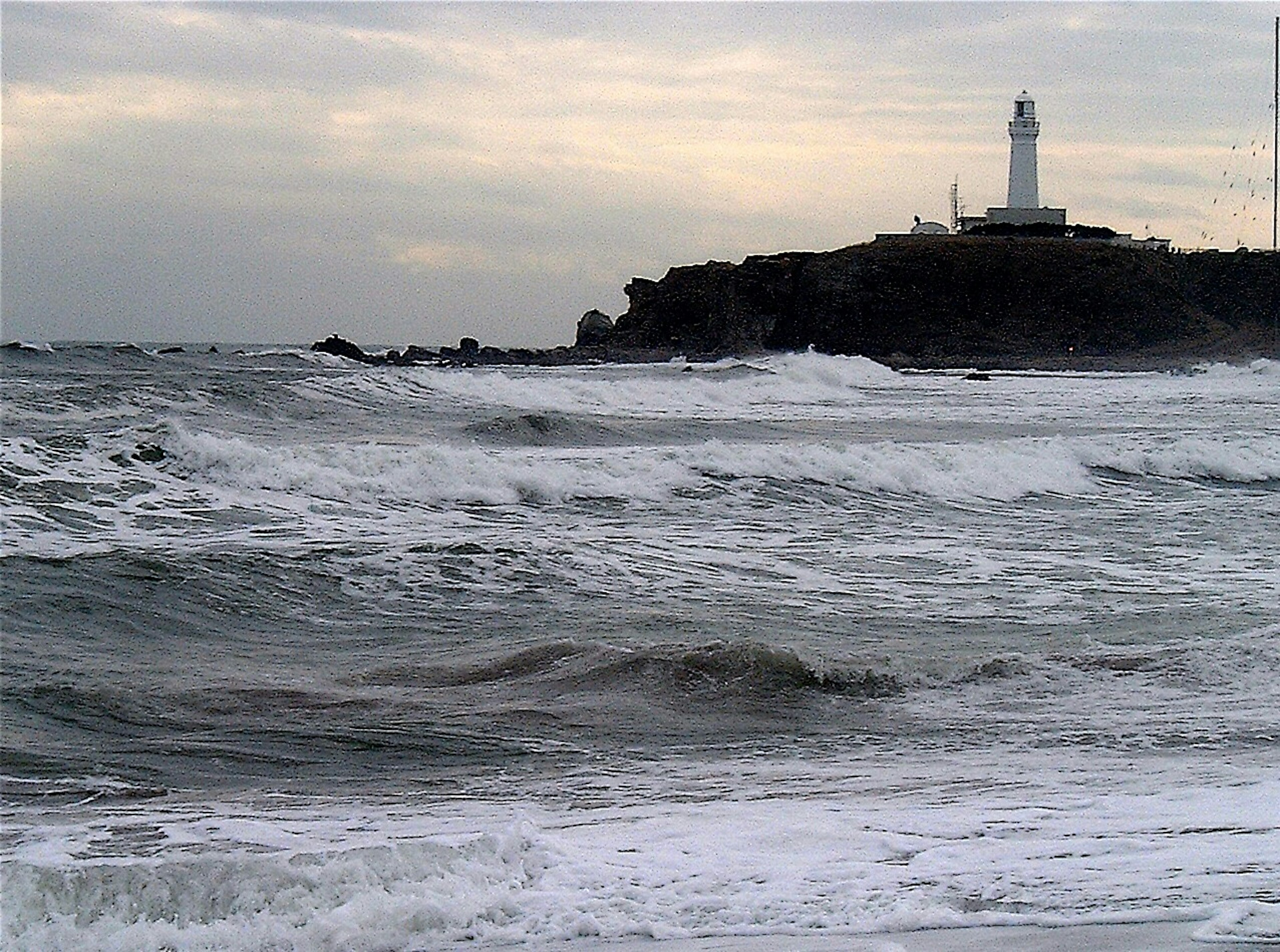 Raue See mit einem Leuchtturm im Hintergrund