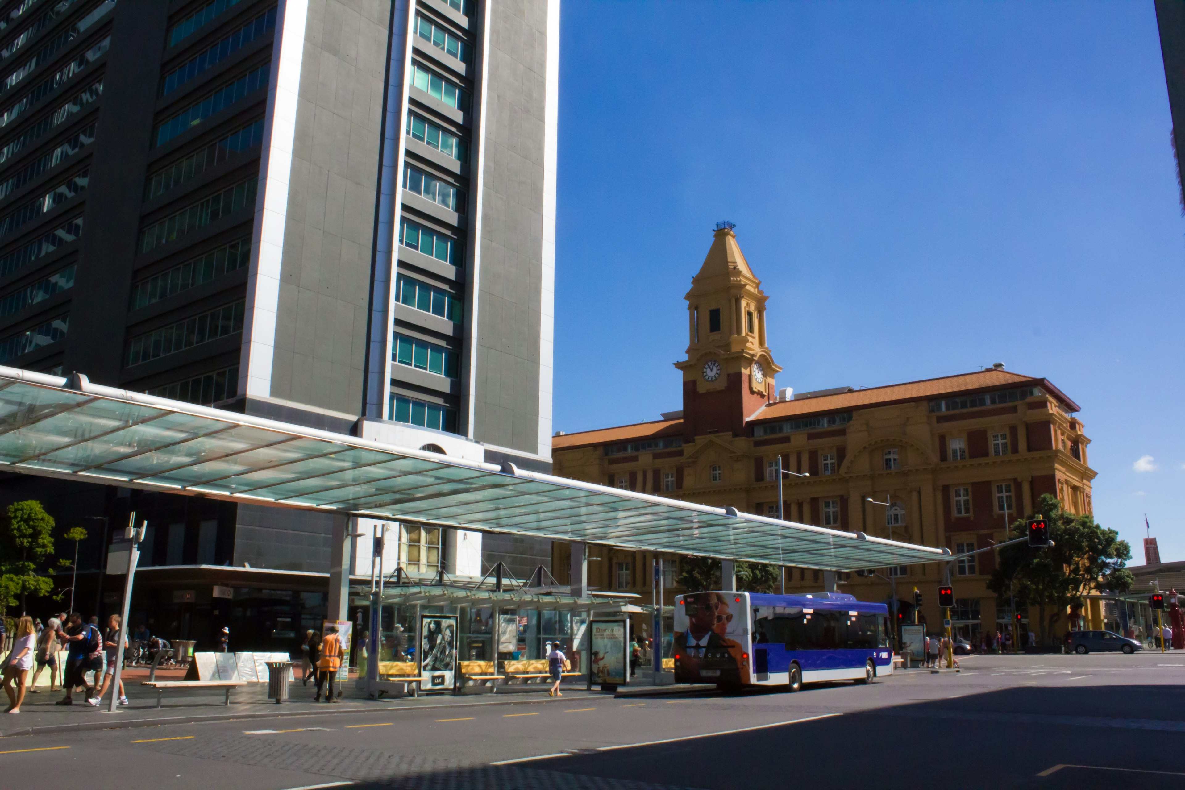 Vue urbaine avec un gratte-ciel moderne et un bâtiment historique avec un arrêt de bus sous un ciel bleu clair