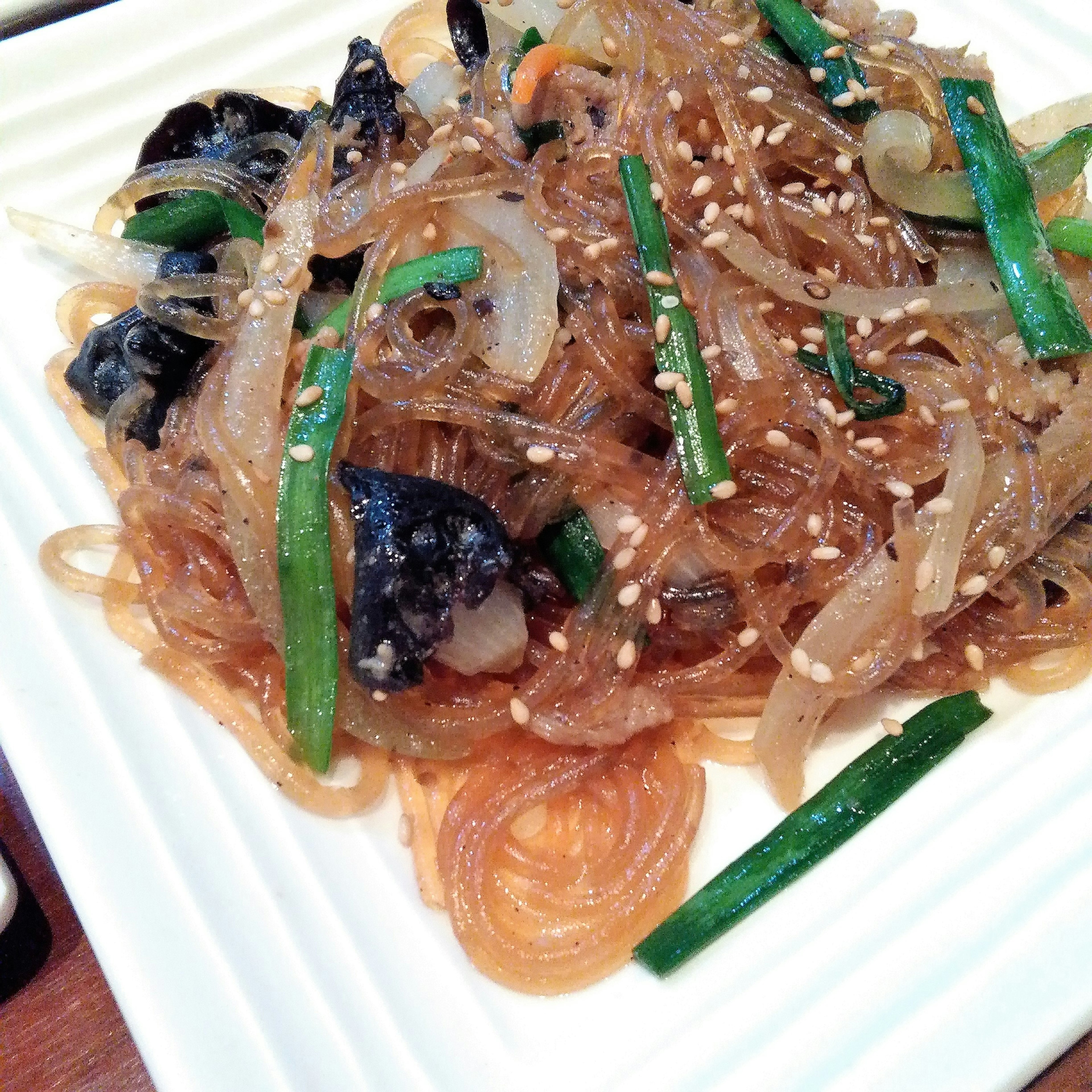 Plate of Korean japchae with glass noodles vegetables and sesame seeds