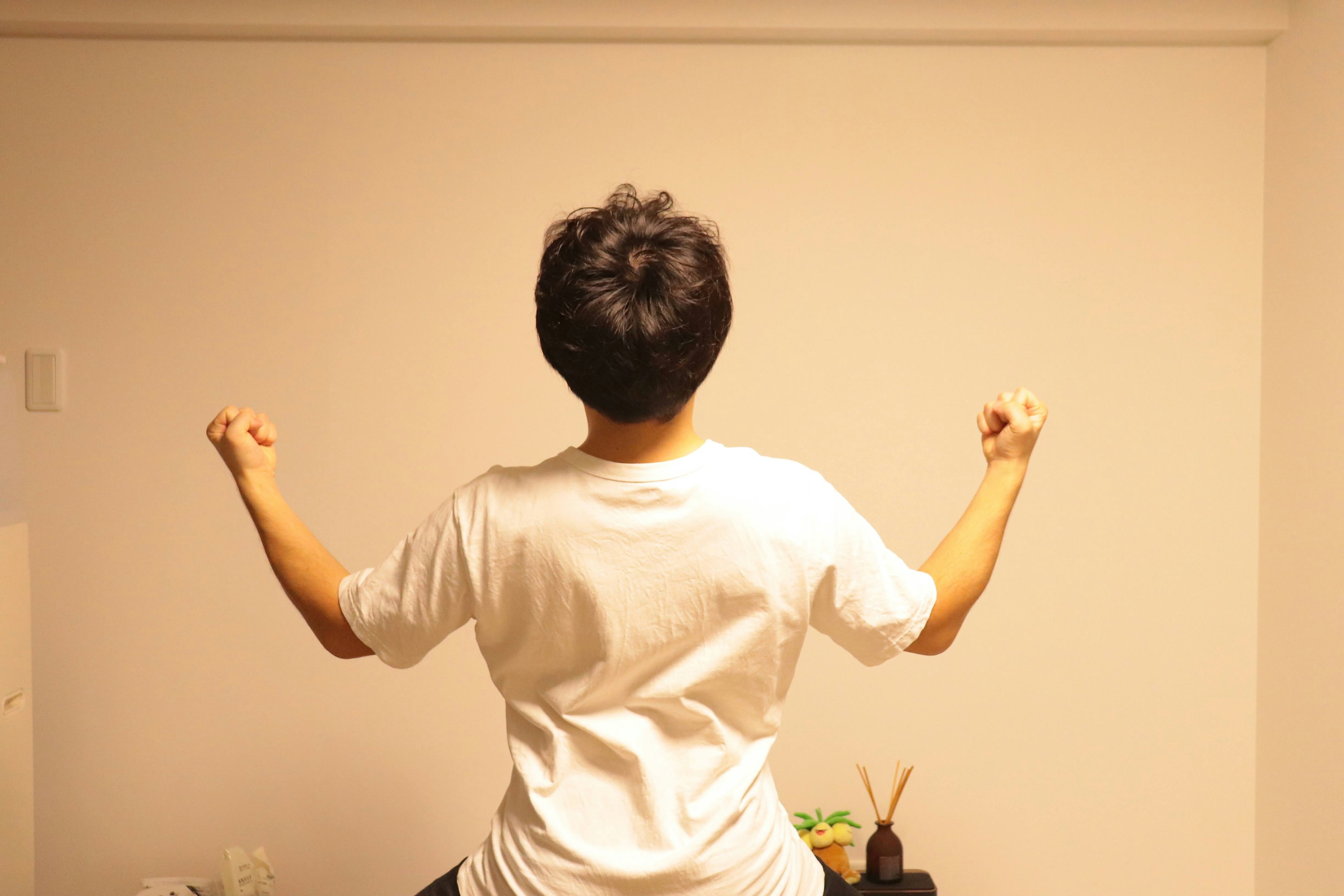 Person with back turned raising both hands in a room